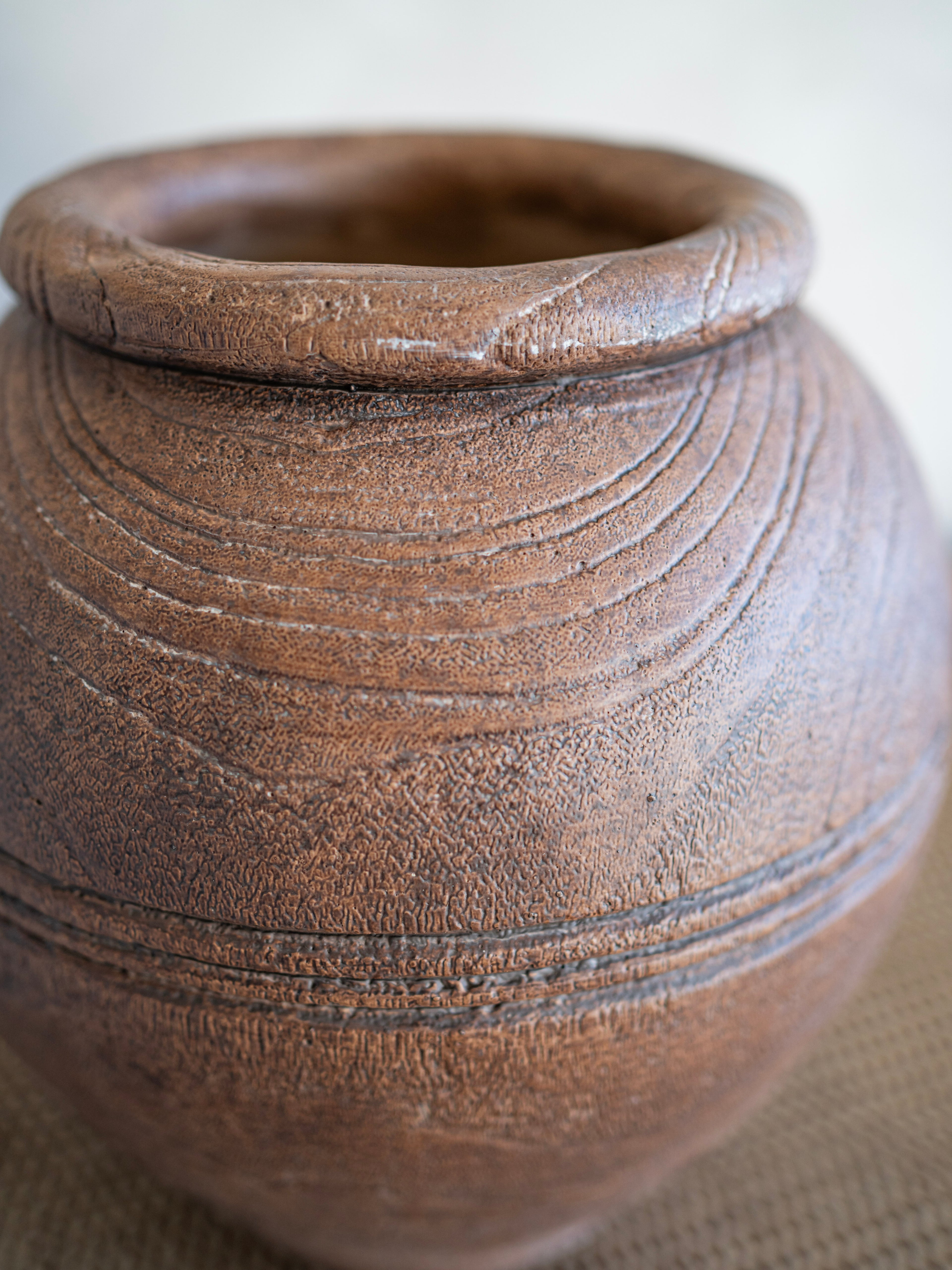 Close-up of a brown ceramic pot with visible texture on a neutral background