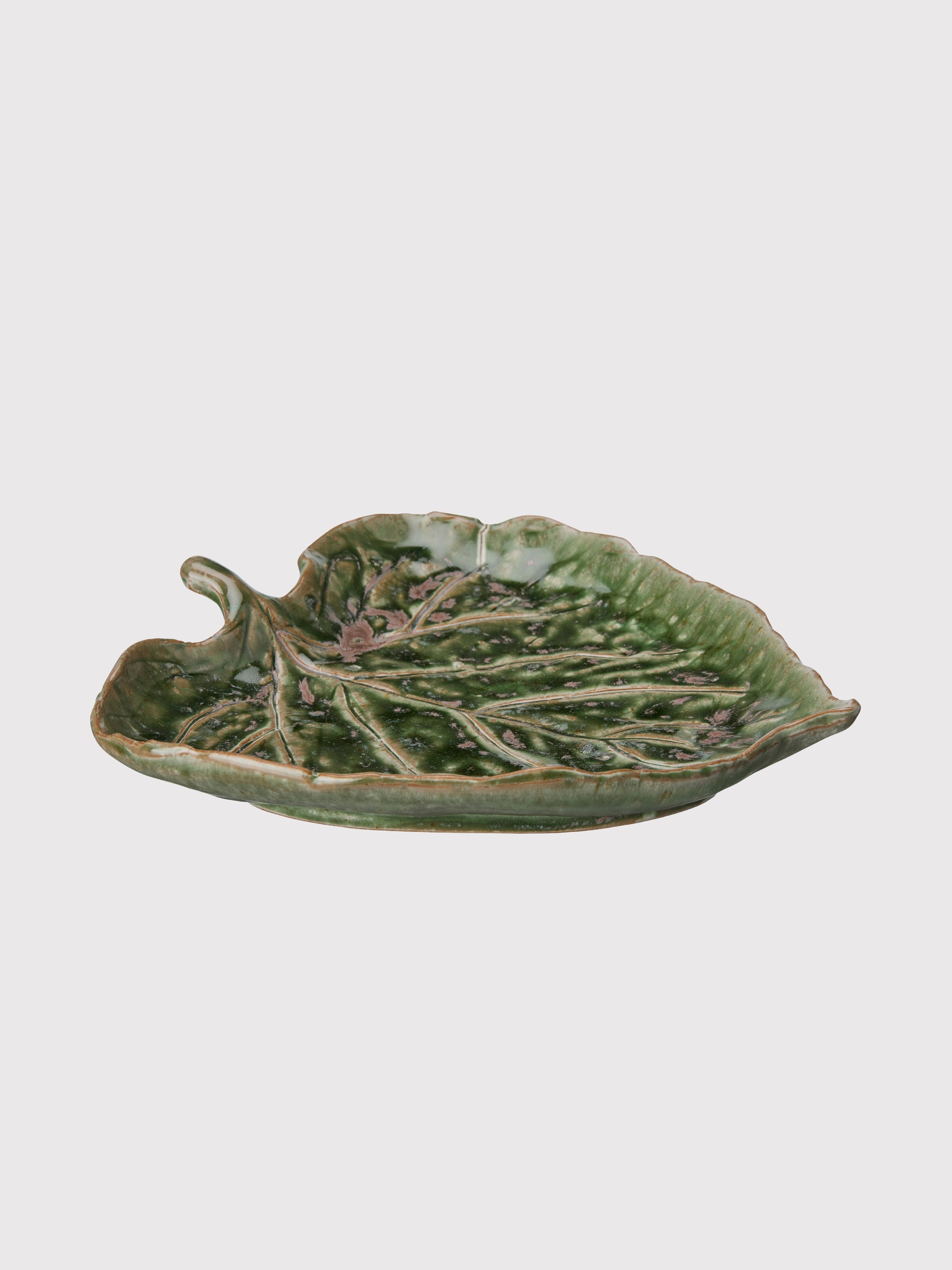 Green ceramic leaf-shaped dish on a white background