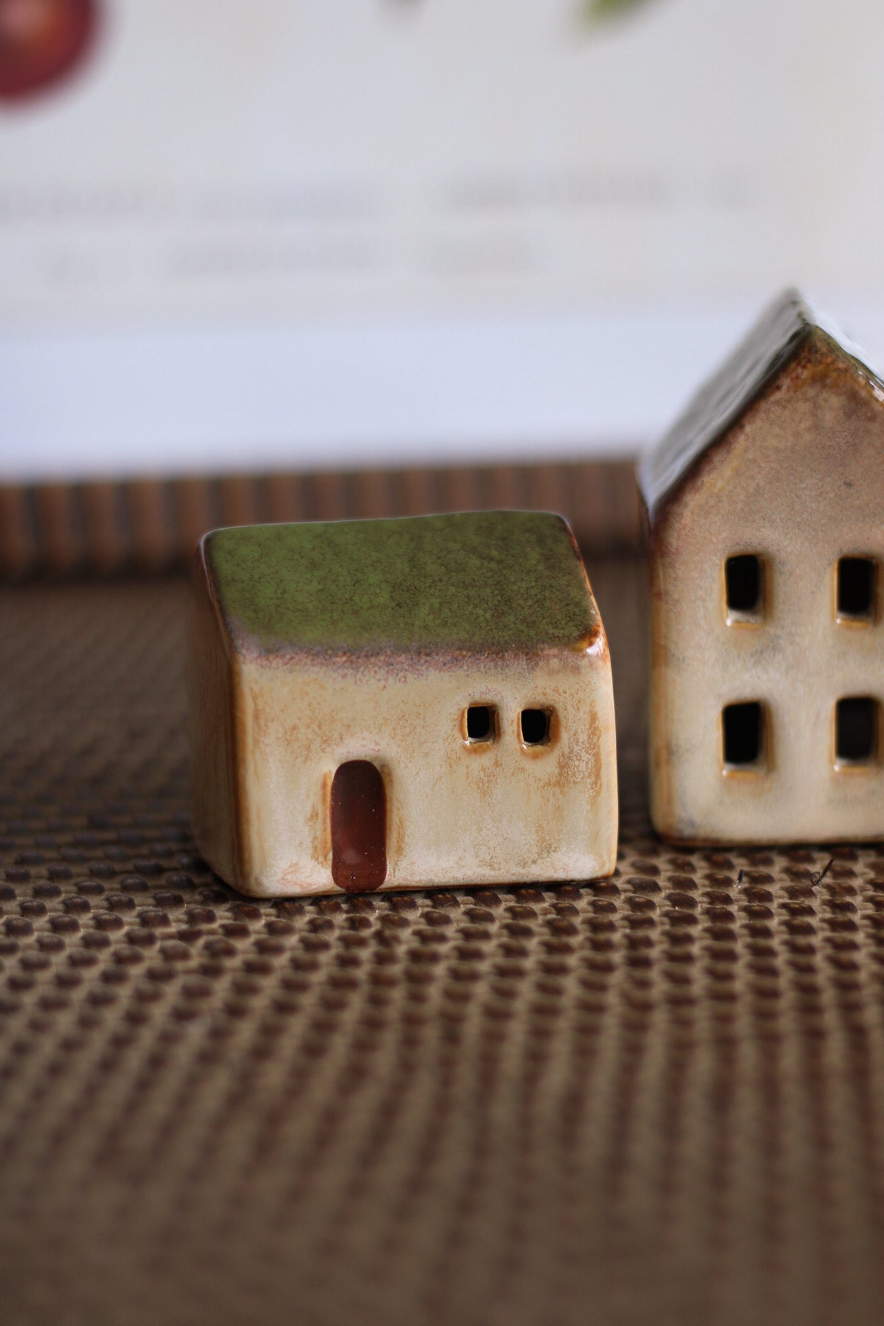 Two small ceramic houses on a textured surface with a blurred background