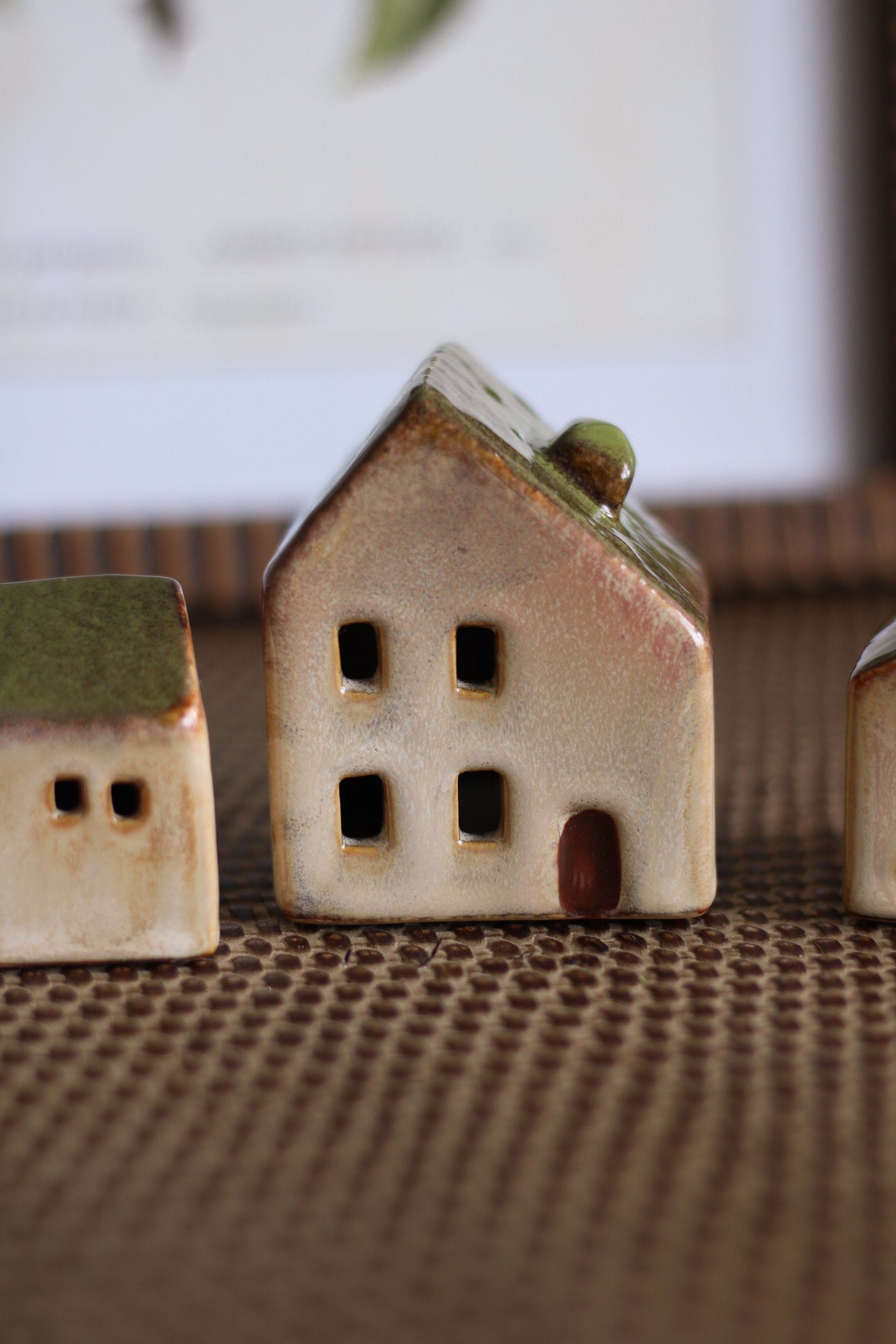 Three ceramic houses on a textured surface with a blurred background