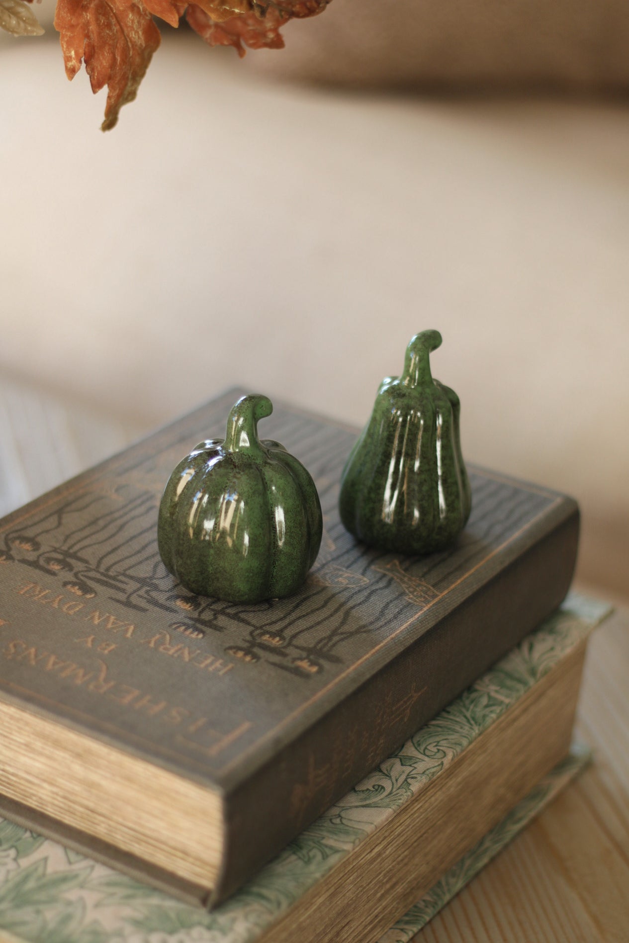 Two green ceramic pumpkins on an open book with a blurred background