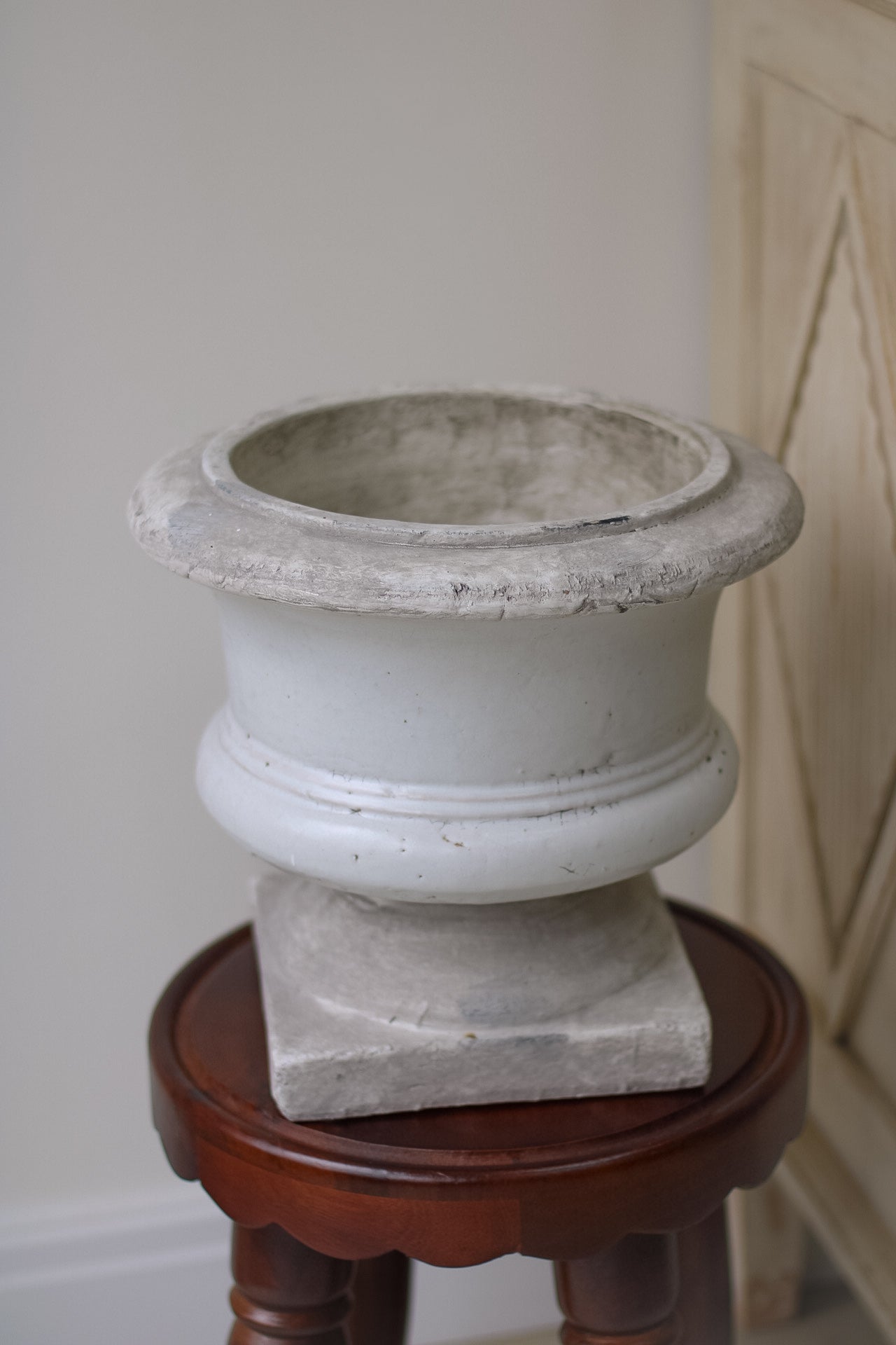 Cement planter on a wooden stand against a neutral wall