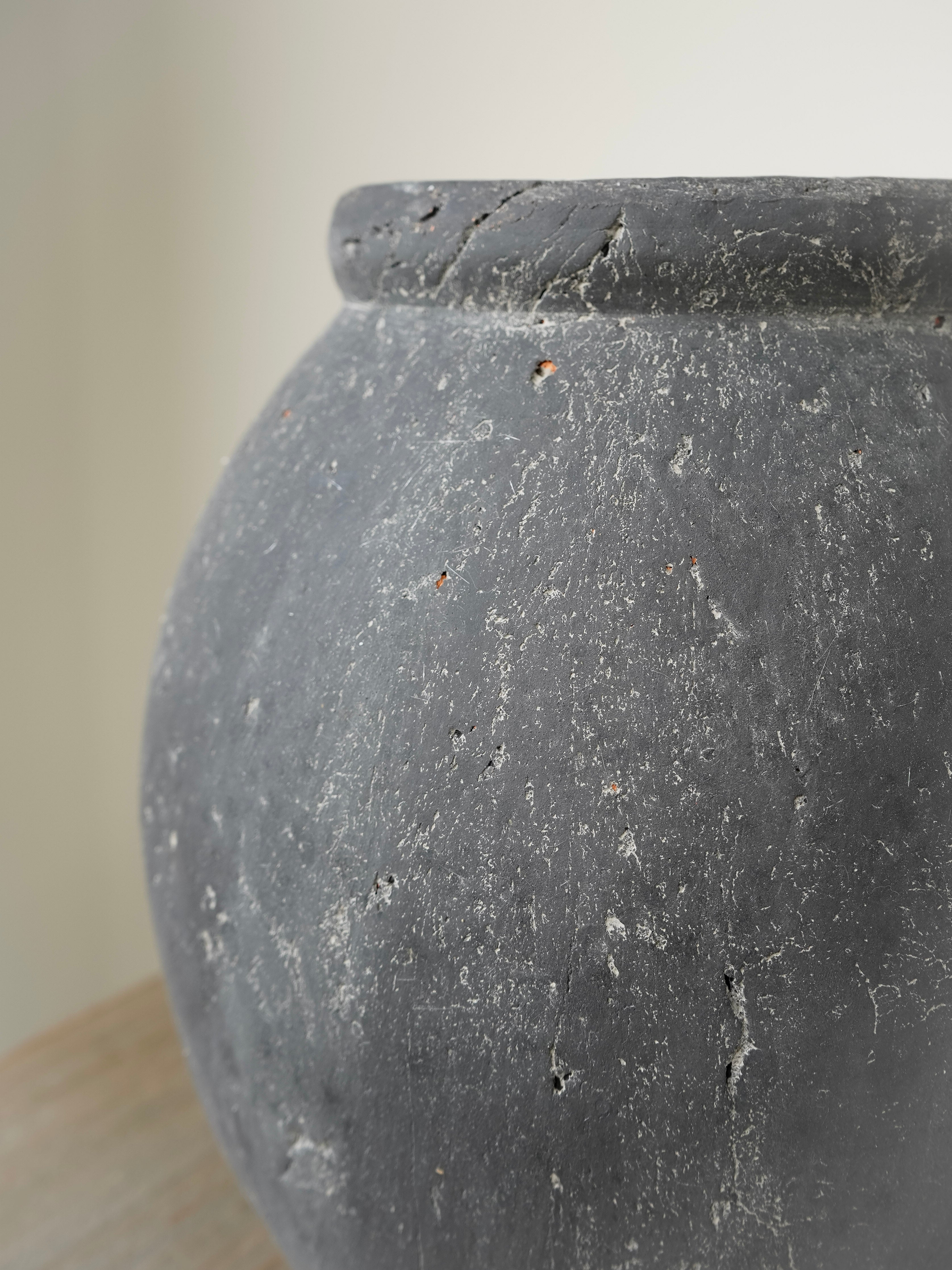 Gray terracotta pot on a light wooden surface with a neutral background