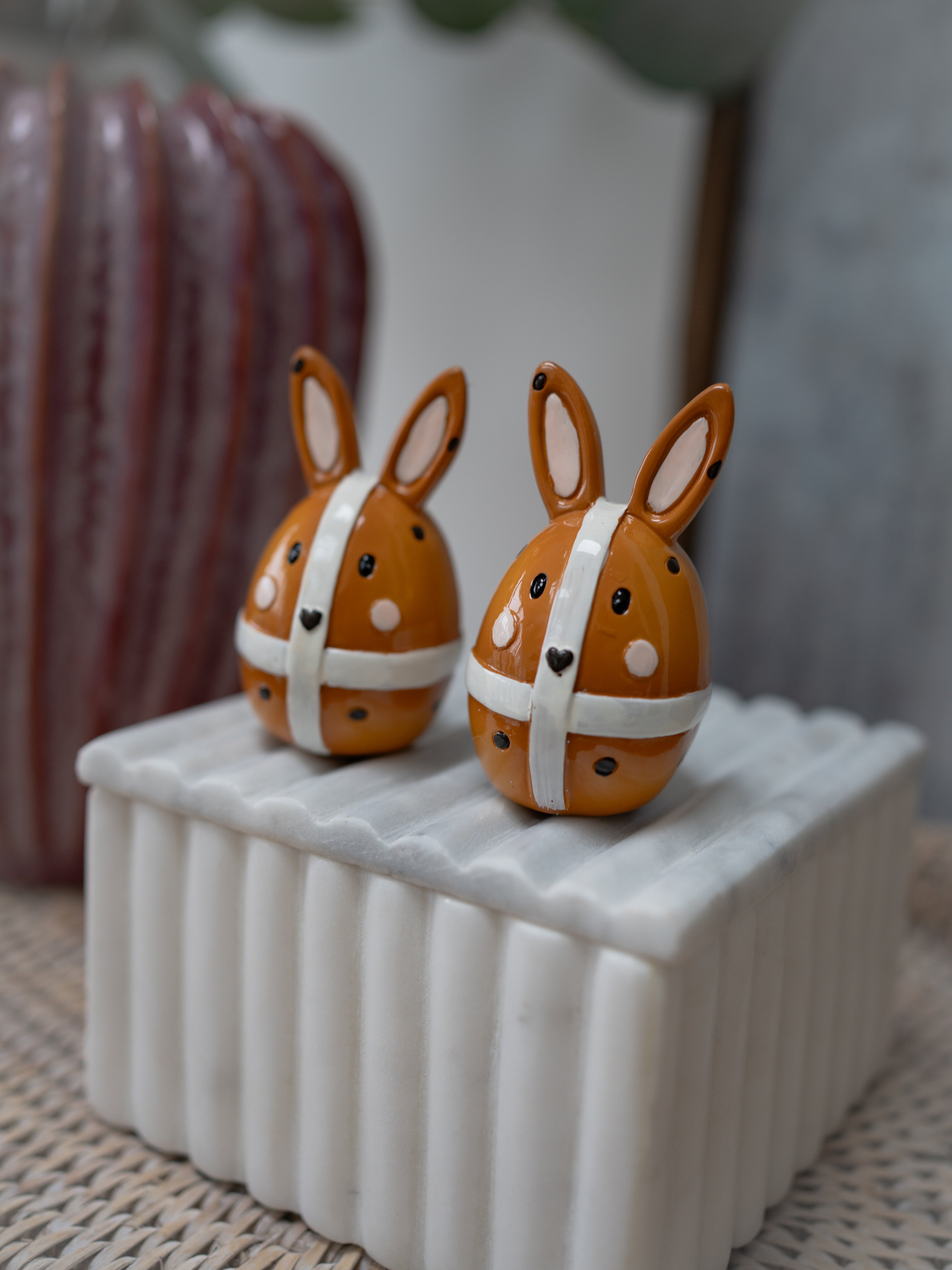 Two small rabbit-shaped objects on a white rectangular base with a blurred background.