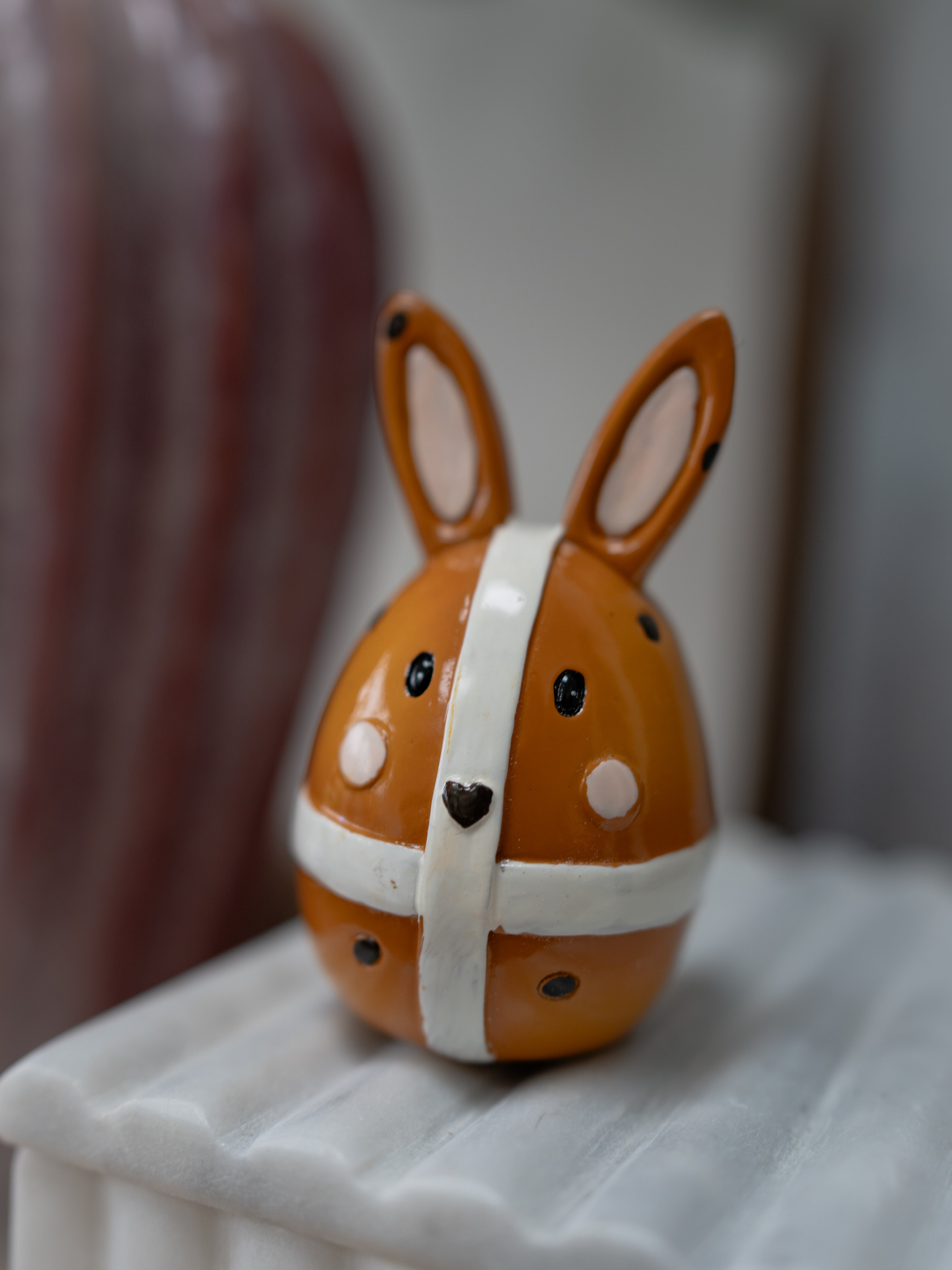 Decorative rabbit figurine with a white bow on a white surface