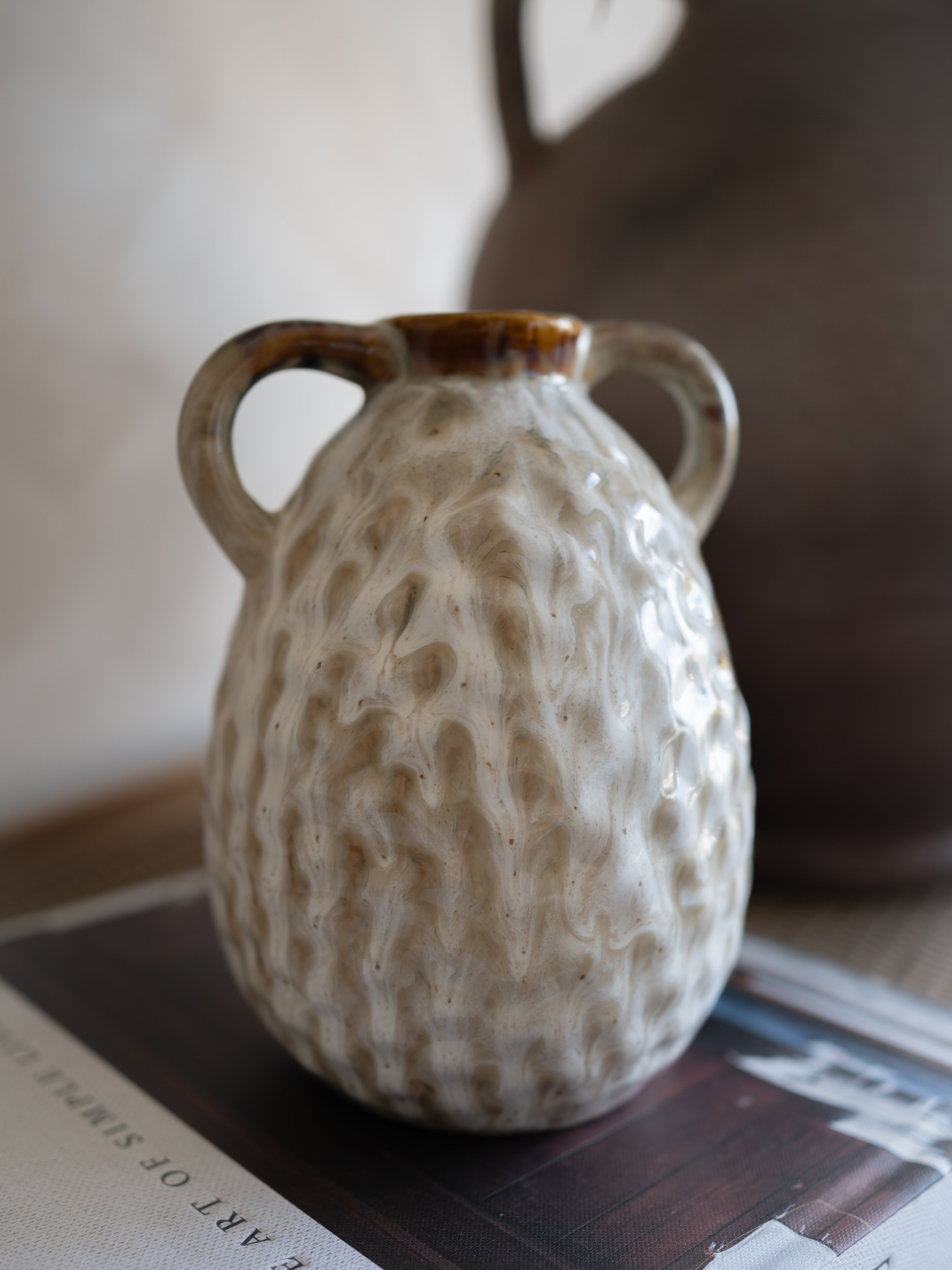 Textured ceramic vase with handles on a surface