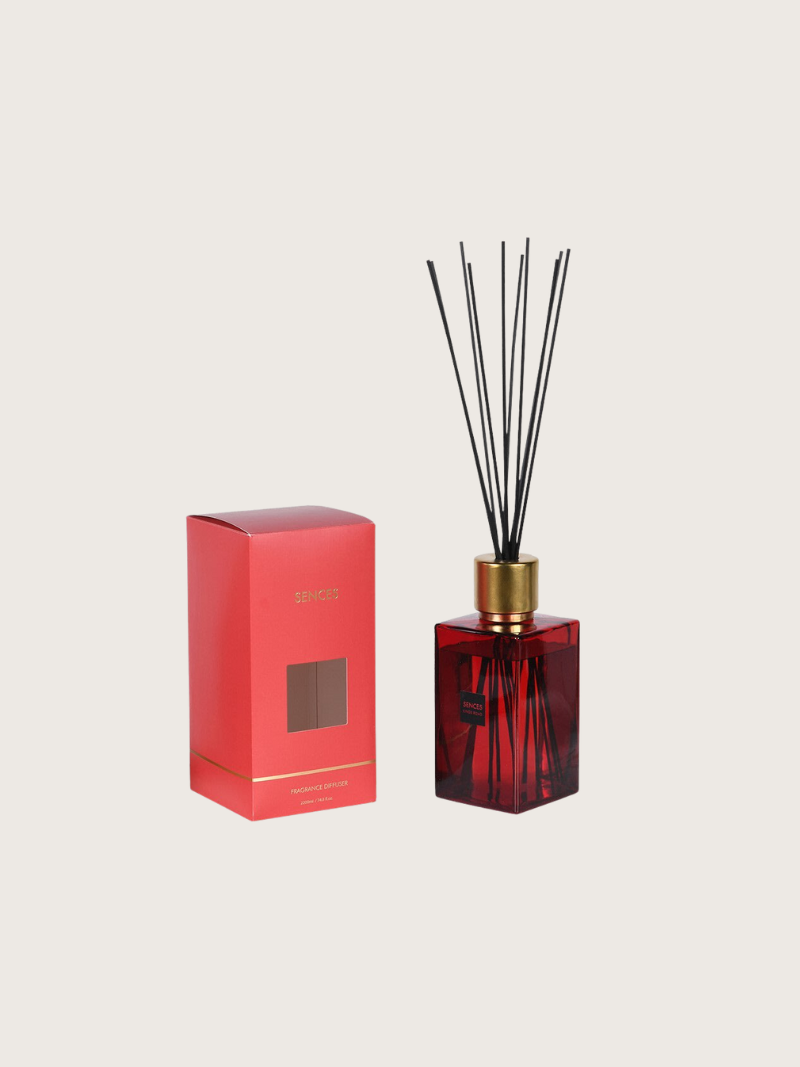 Red diffuser bottle with gold cap and red packaging on a beige background