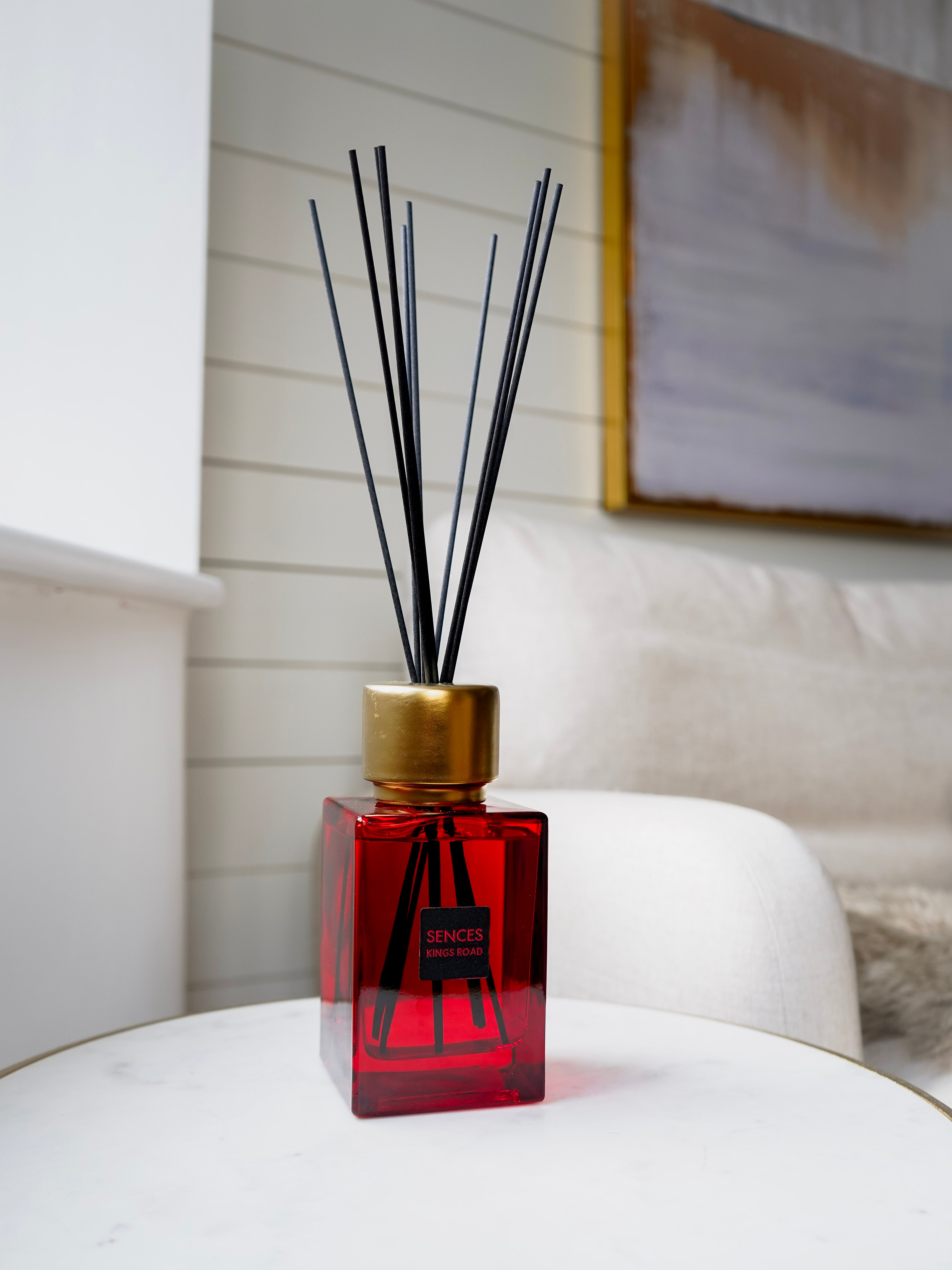 Red sences kings road diffuser with black sticks on a white surface, blurred background