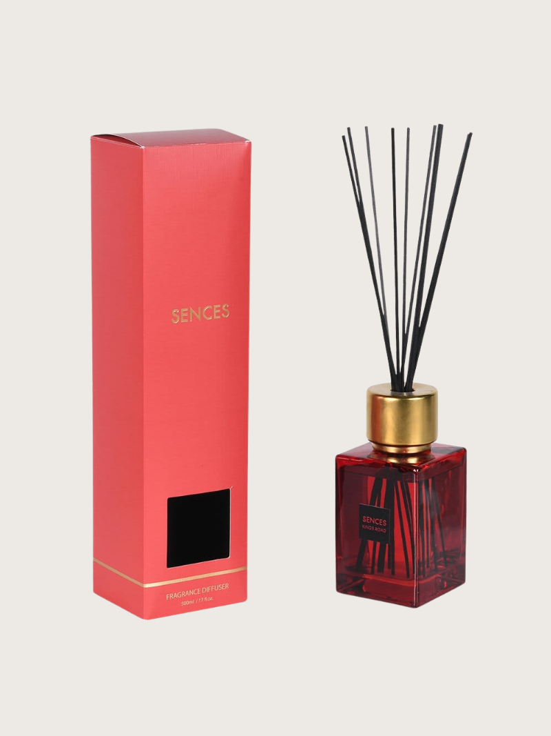 Red kings road sences diffuser bottle with gold cap and black sticks next to its packaging on a light gray background