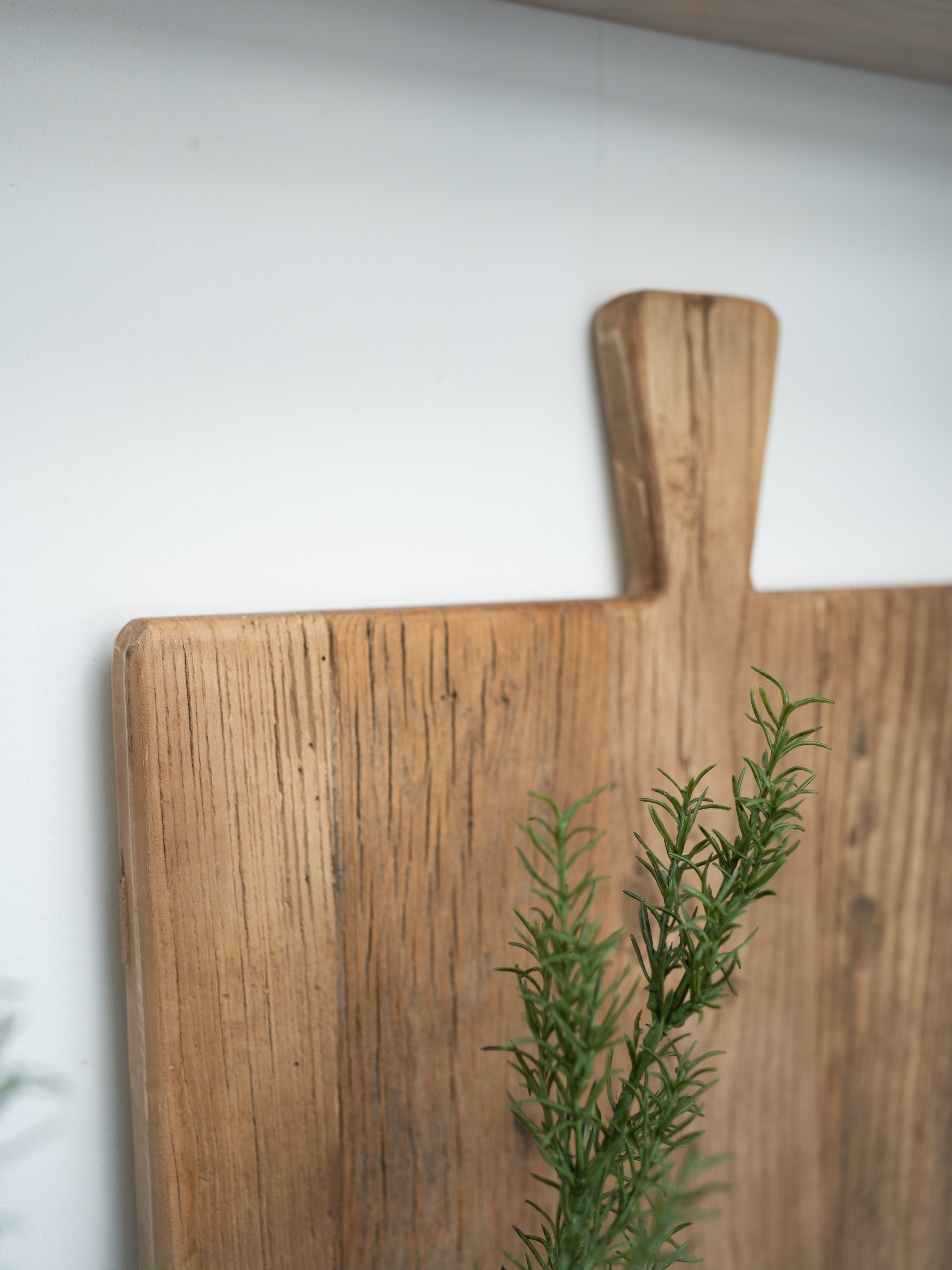 Wooden elm cutting board with a sprig of rosemary on a white background