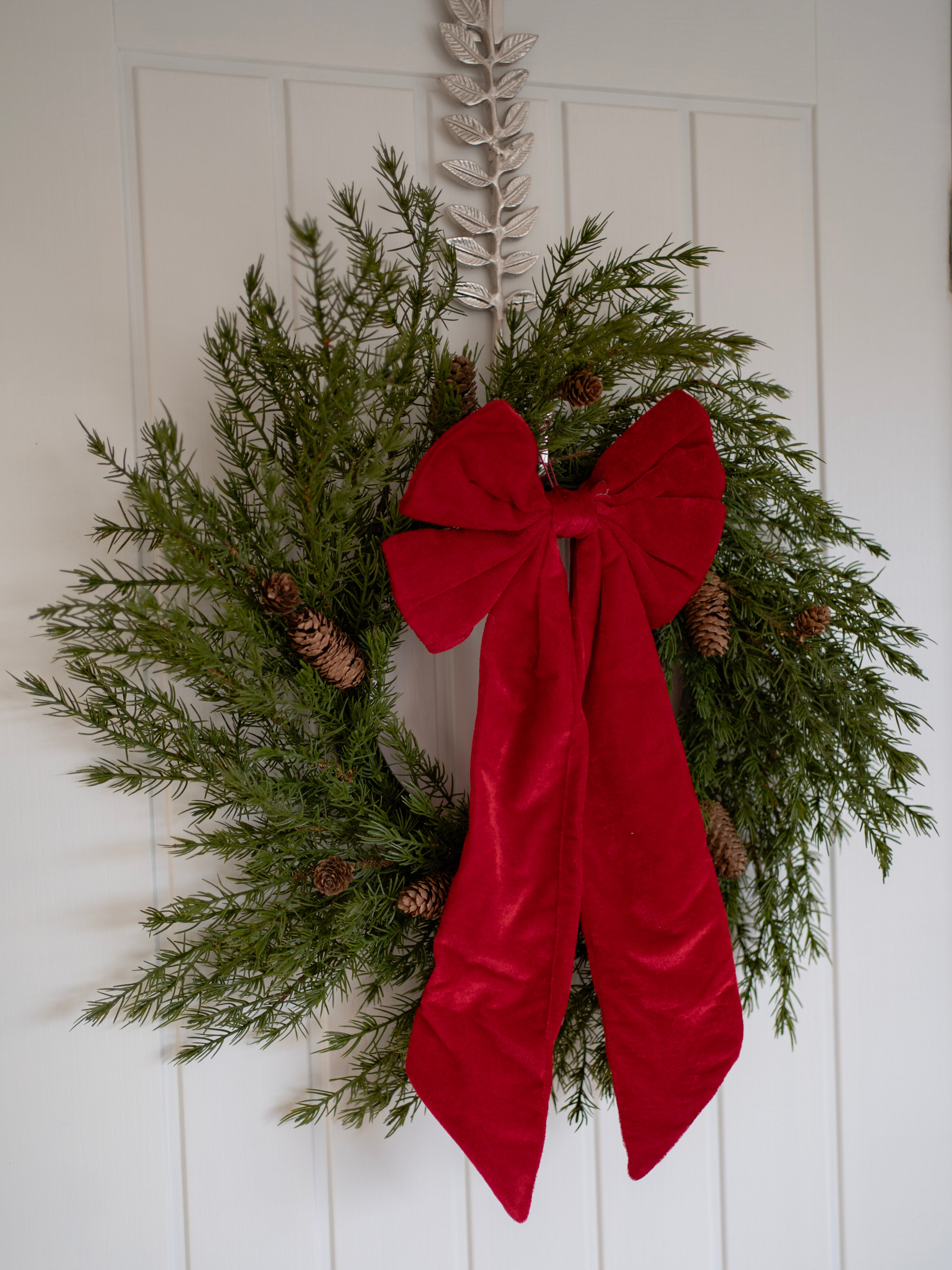 Christmas wreath with a red bow on a white door