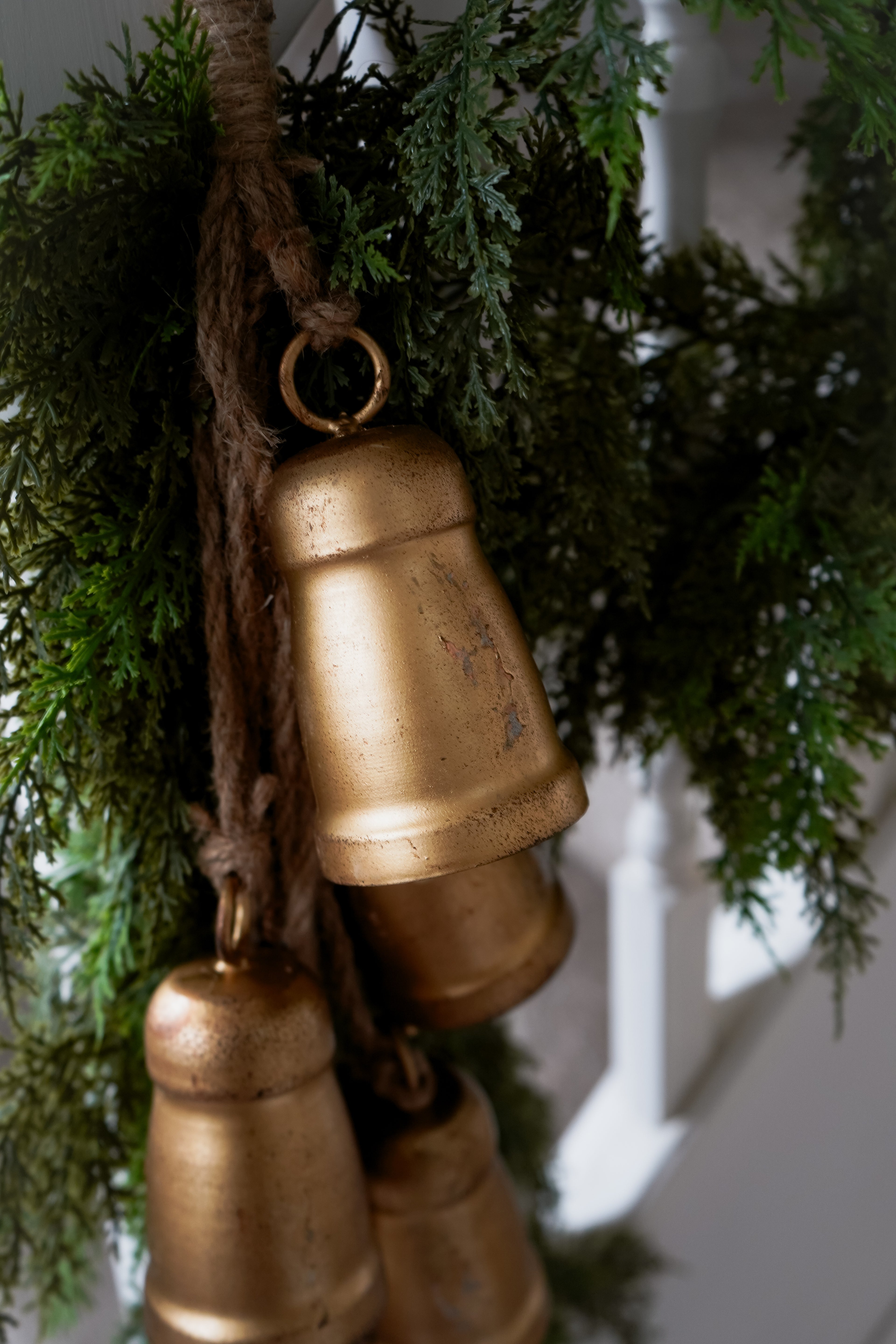 Bronze bells hanging from greenery against a blurred background