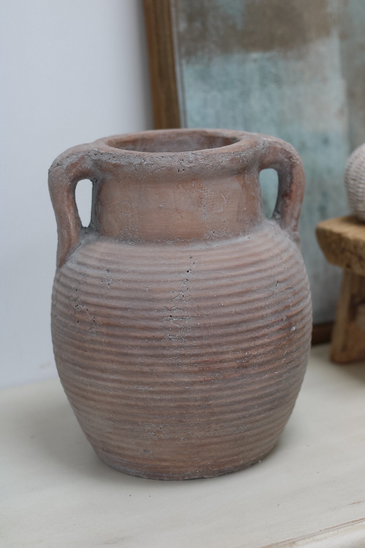 Terracotta vase with ribbed texture on a light surface