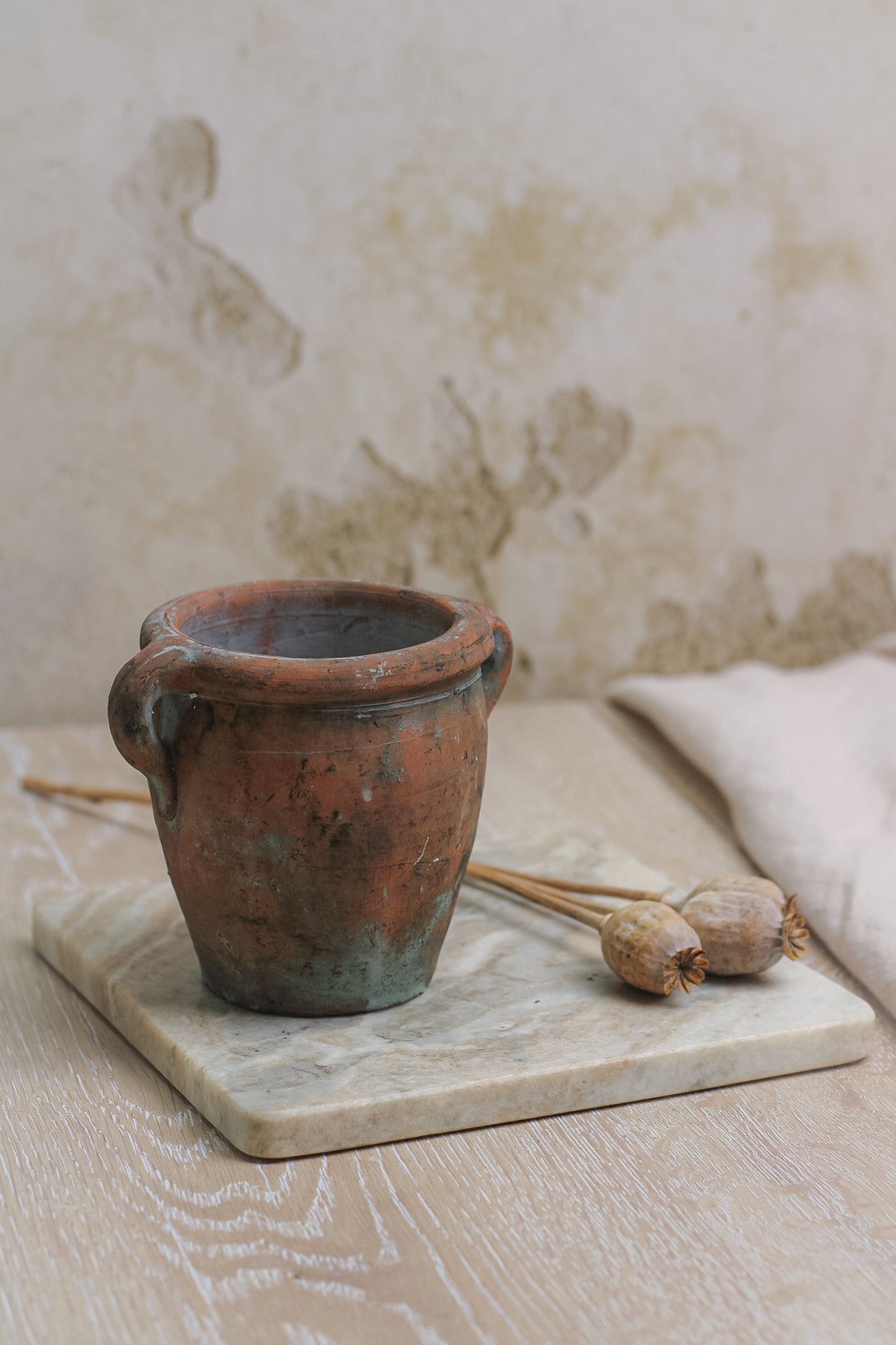 small mini vintage olive pot on marble board with dried poppy heads