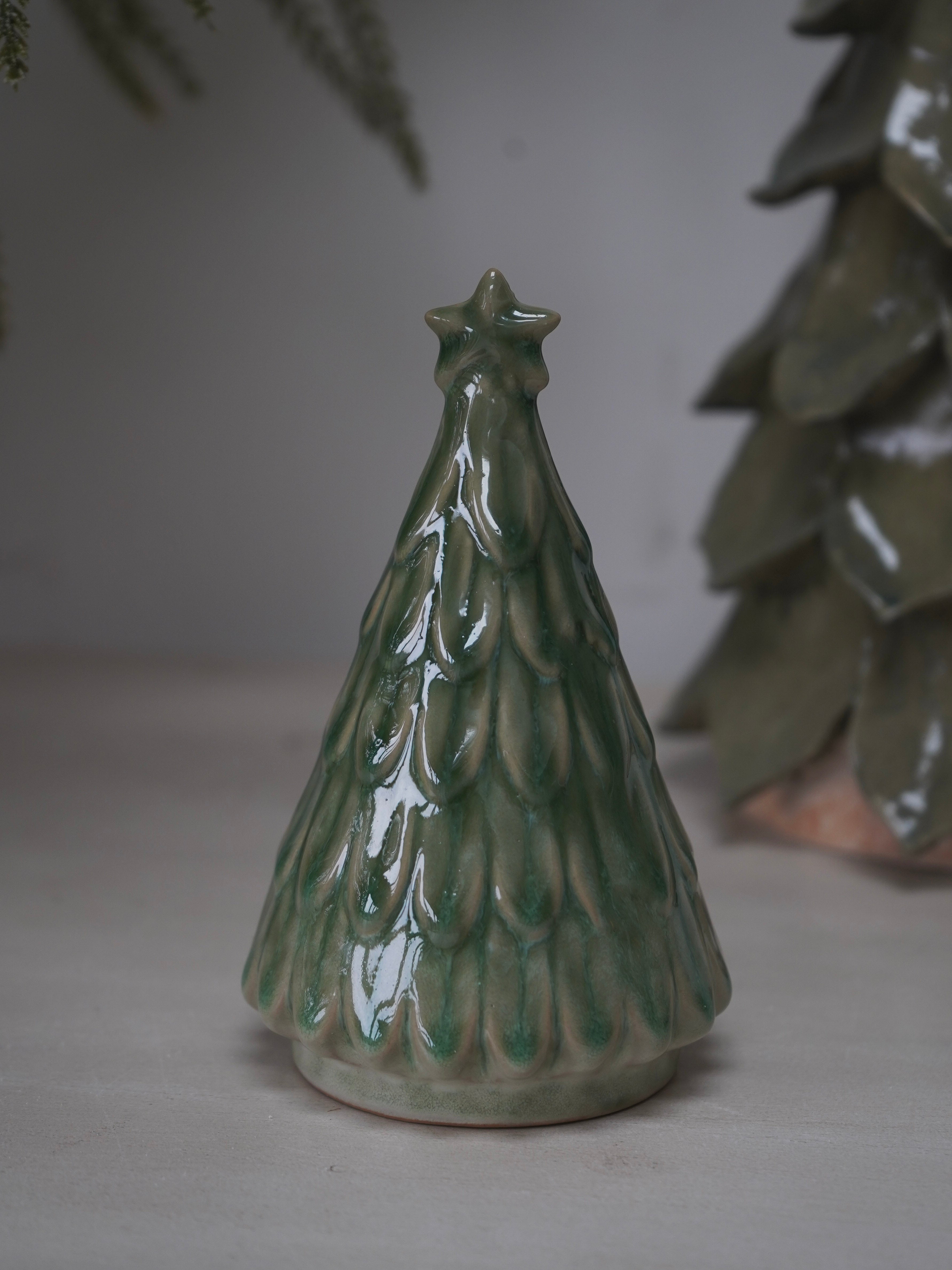 Green ceramic Christmas tree ornament on a neutral background