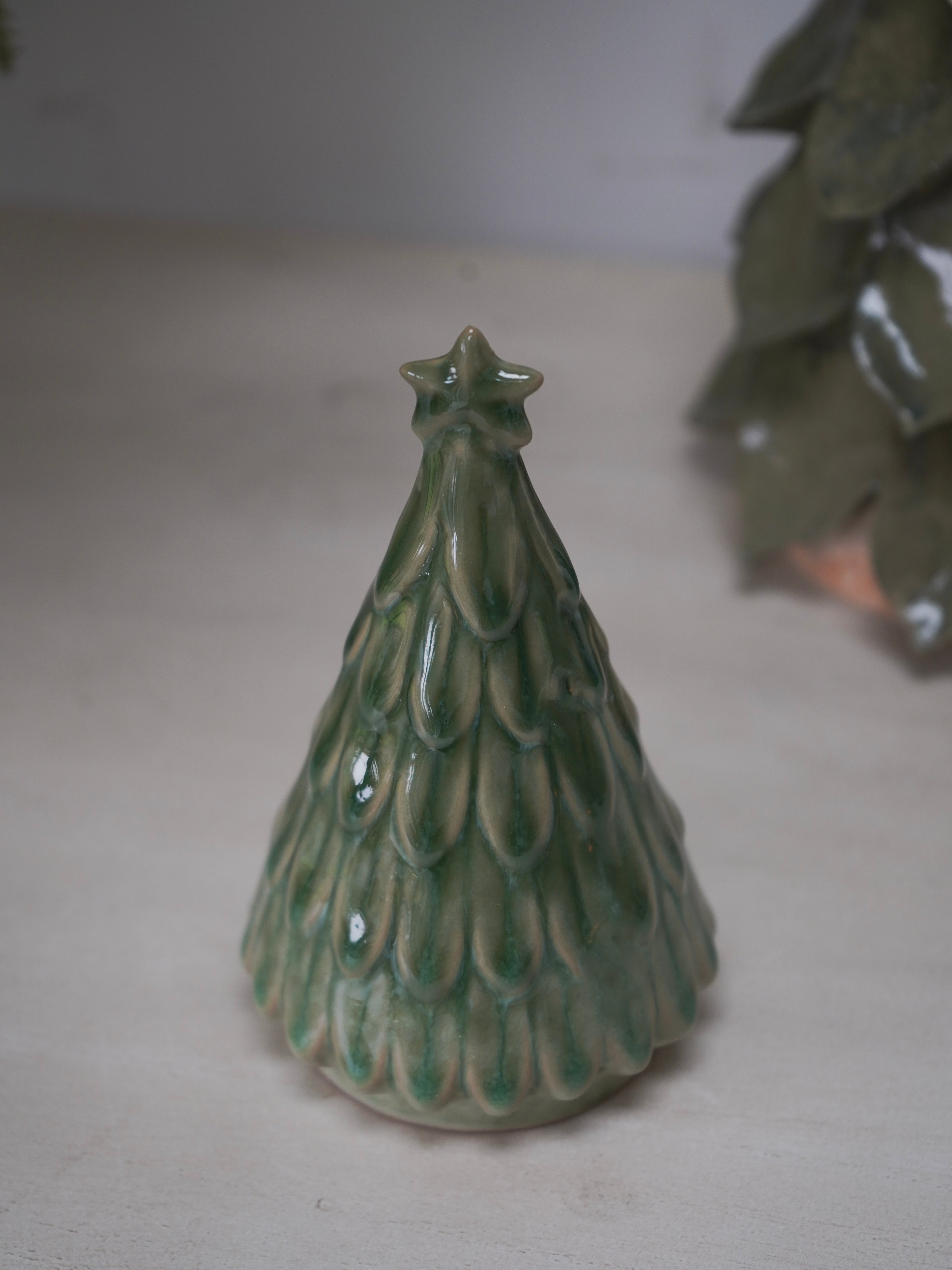 Green ceramic Christmas tree ornament on a light background