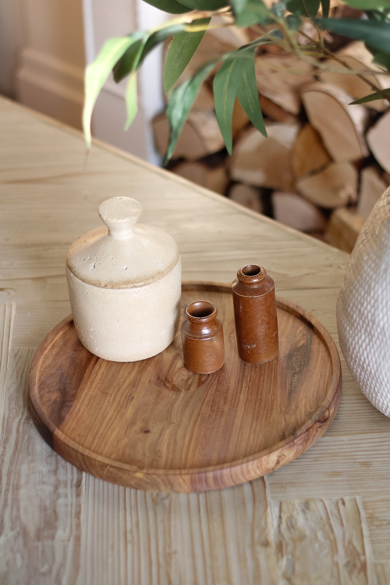 dark wooden round natural tray, styled on coffee table with taupe jar and antique tall vintage ink pots