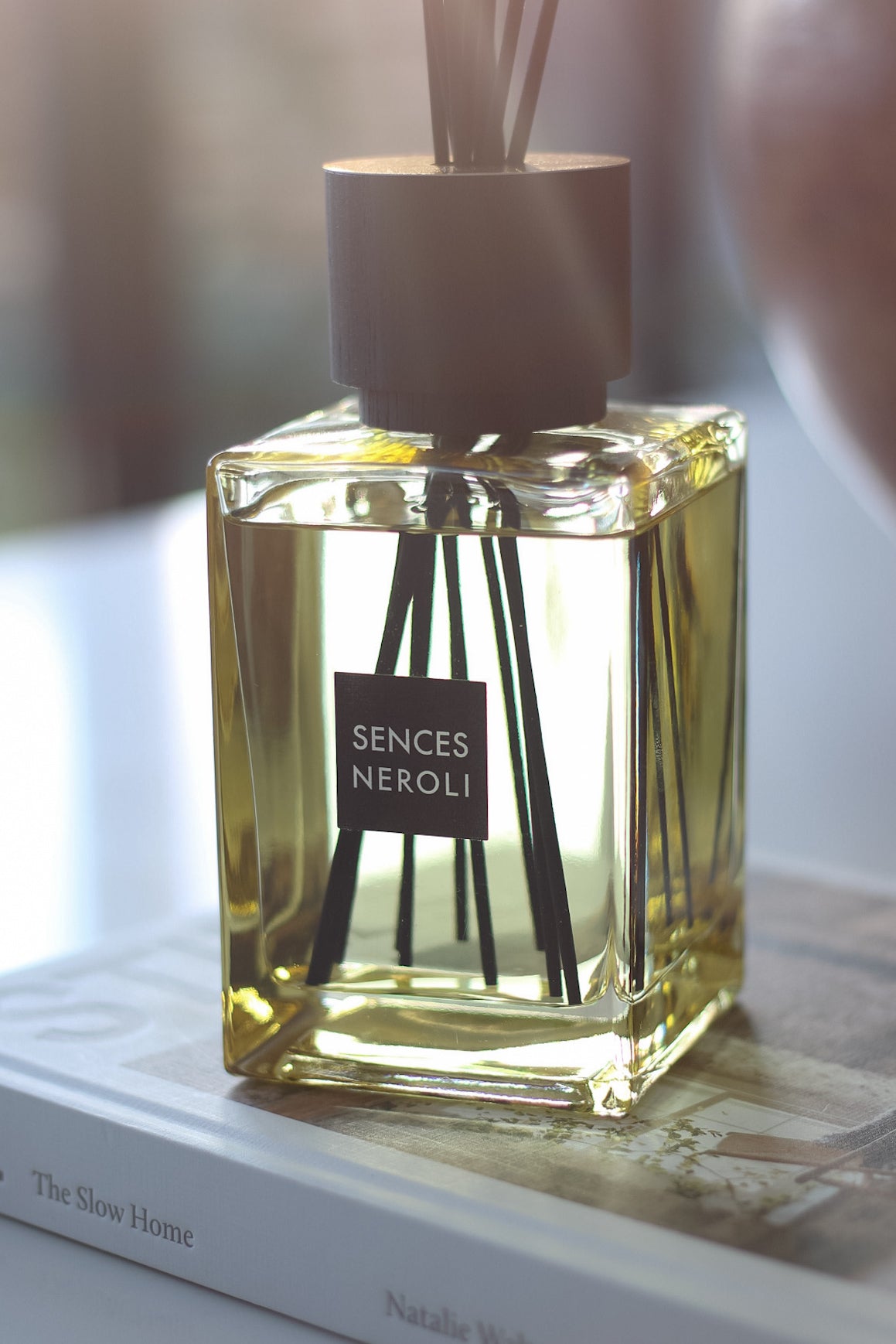 Sences Neroli diffuser bottle on a surface with a blurred background