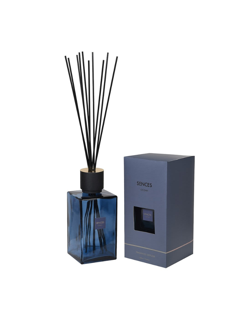 Blue diffuser bottle with black sticks and matching box on a white background