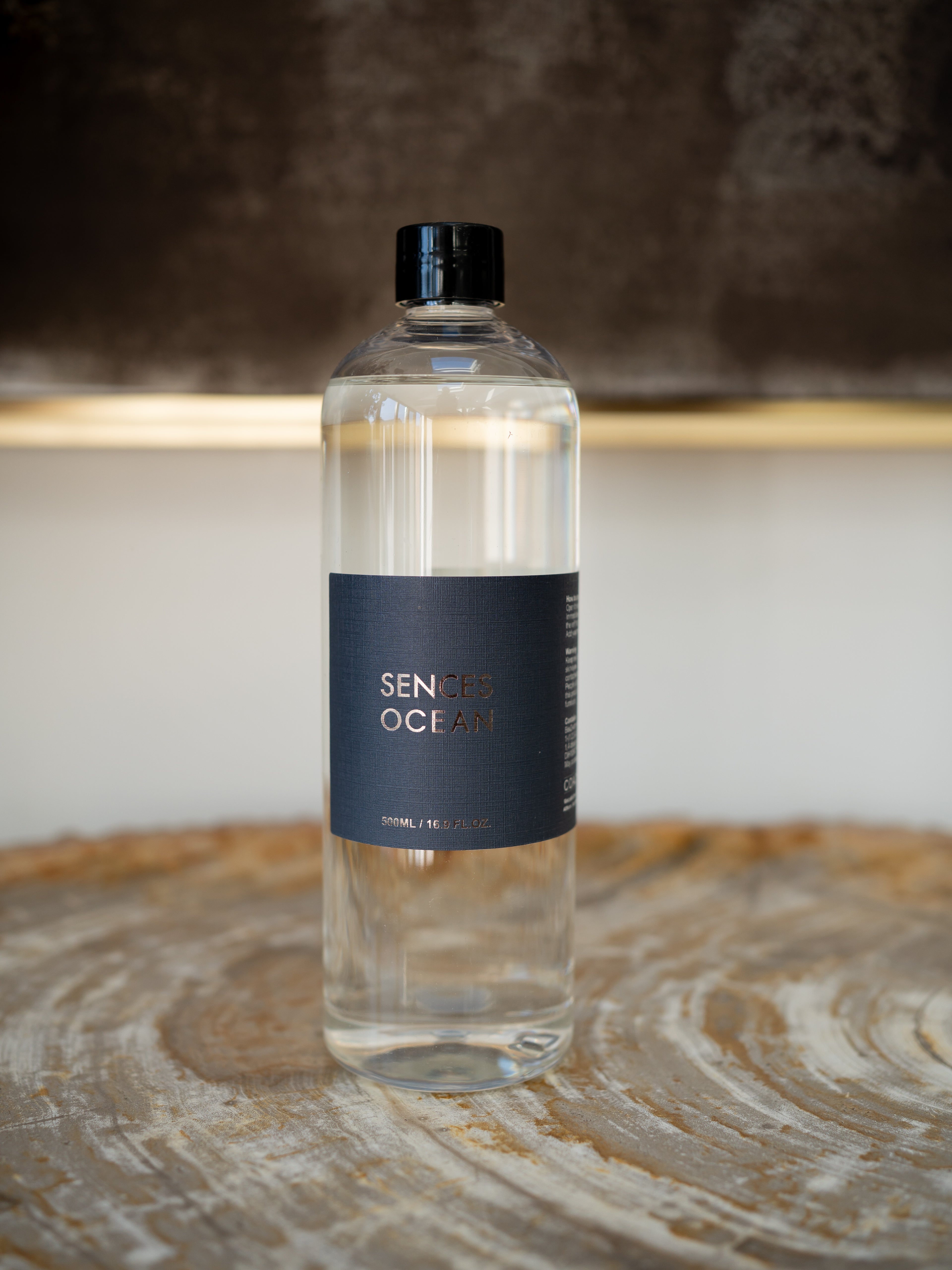 A clear refill bottle of diffuser oil with a black cap and a dark navy label reading &
