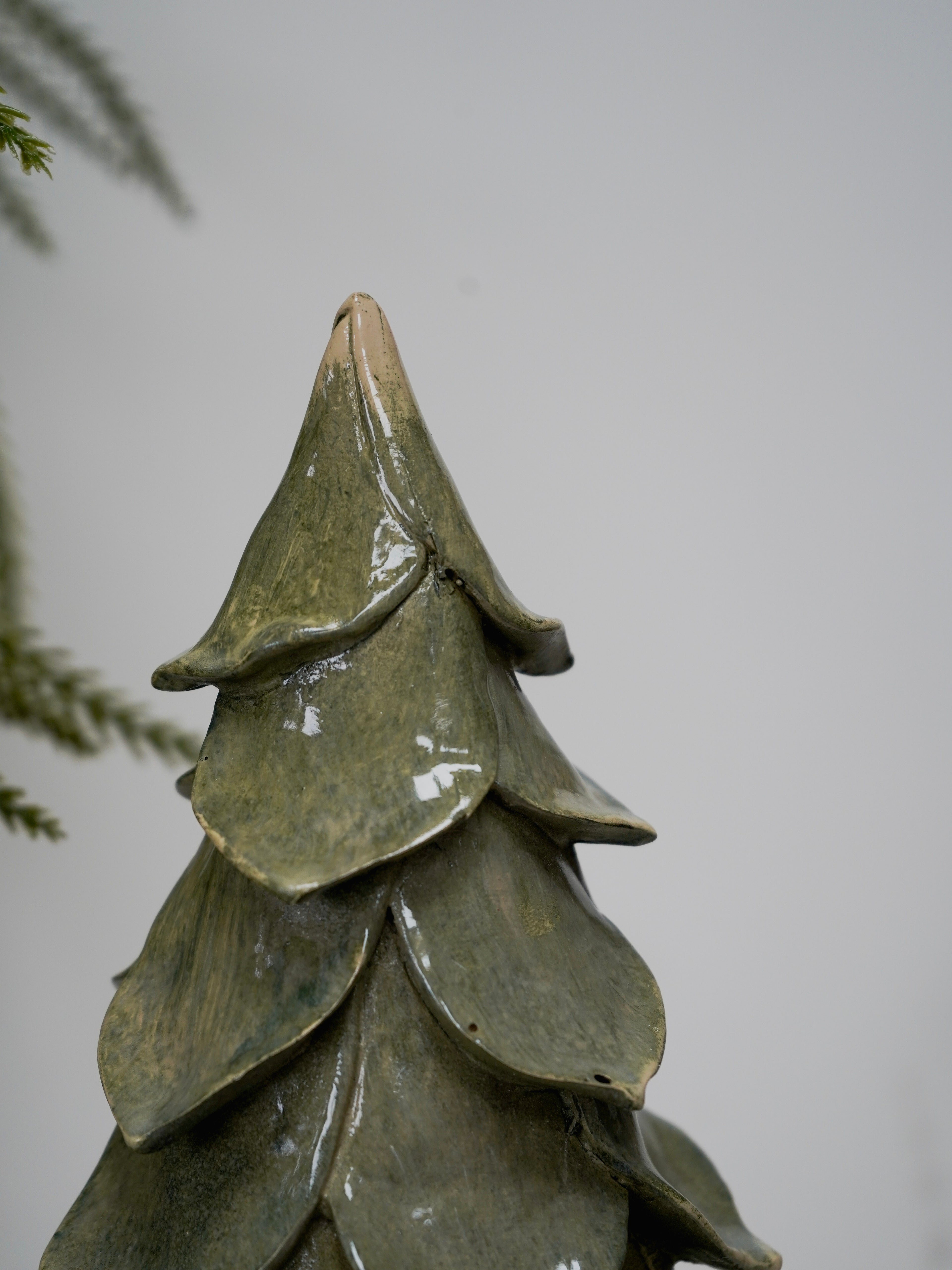 Green ceramic tree-shaped ornament on a plain background