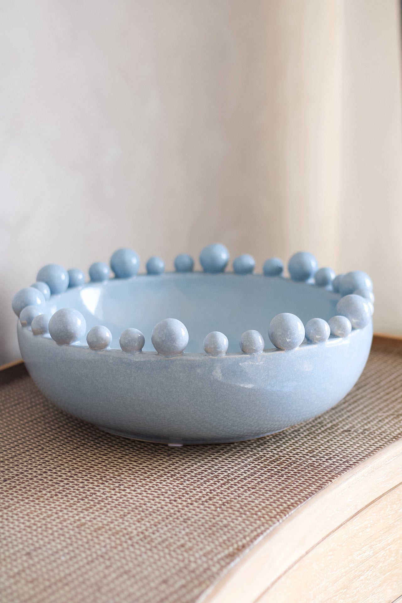 Light blue ceramic bowl with bobble edge detailing on a neutral background