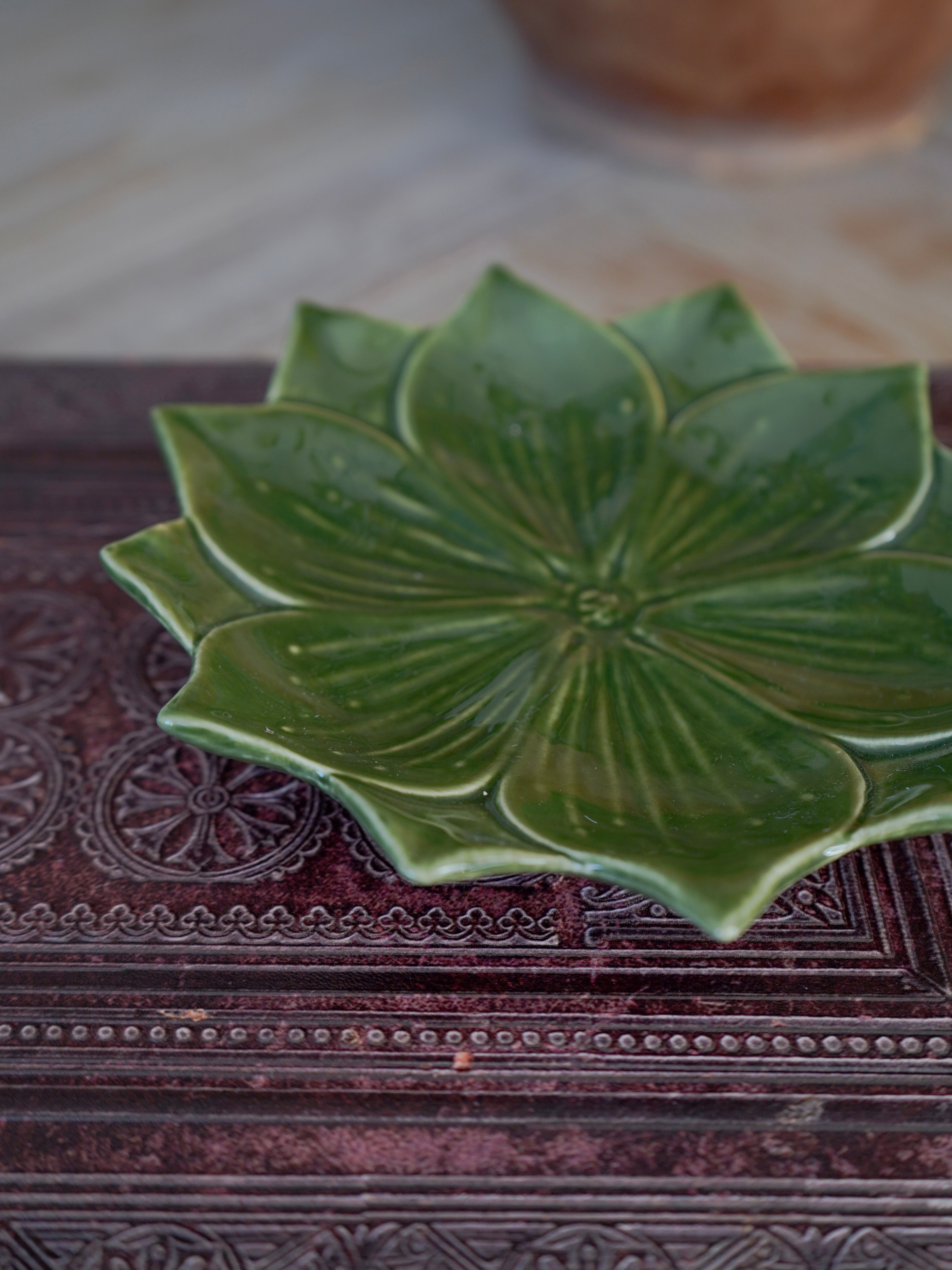 Green ceramic trinket dish with leaf-like design on a textured surface