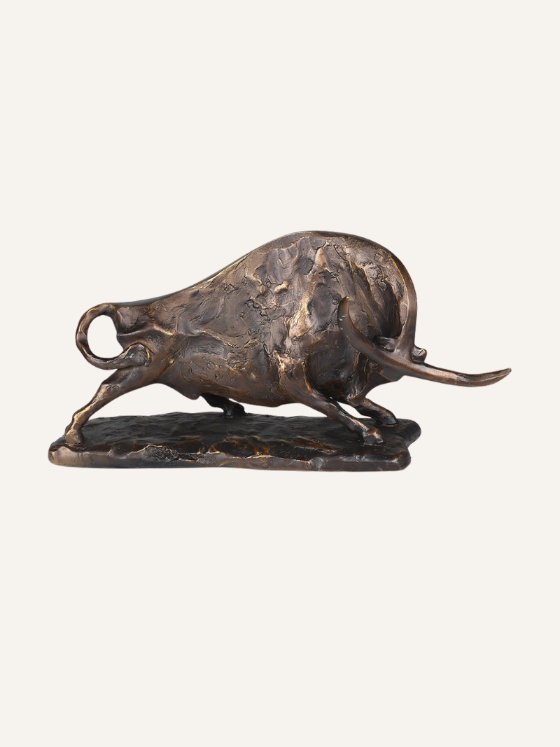 Bronze sculpture of a charging bull on a white background