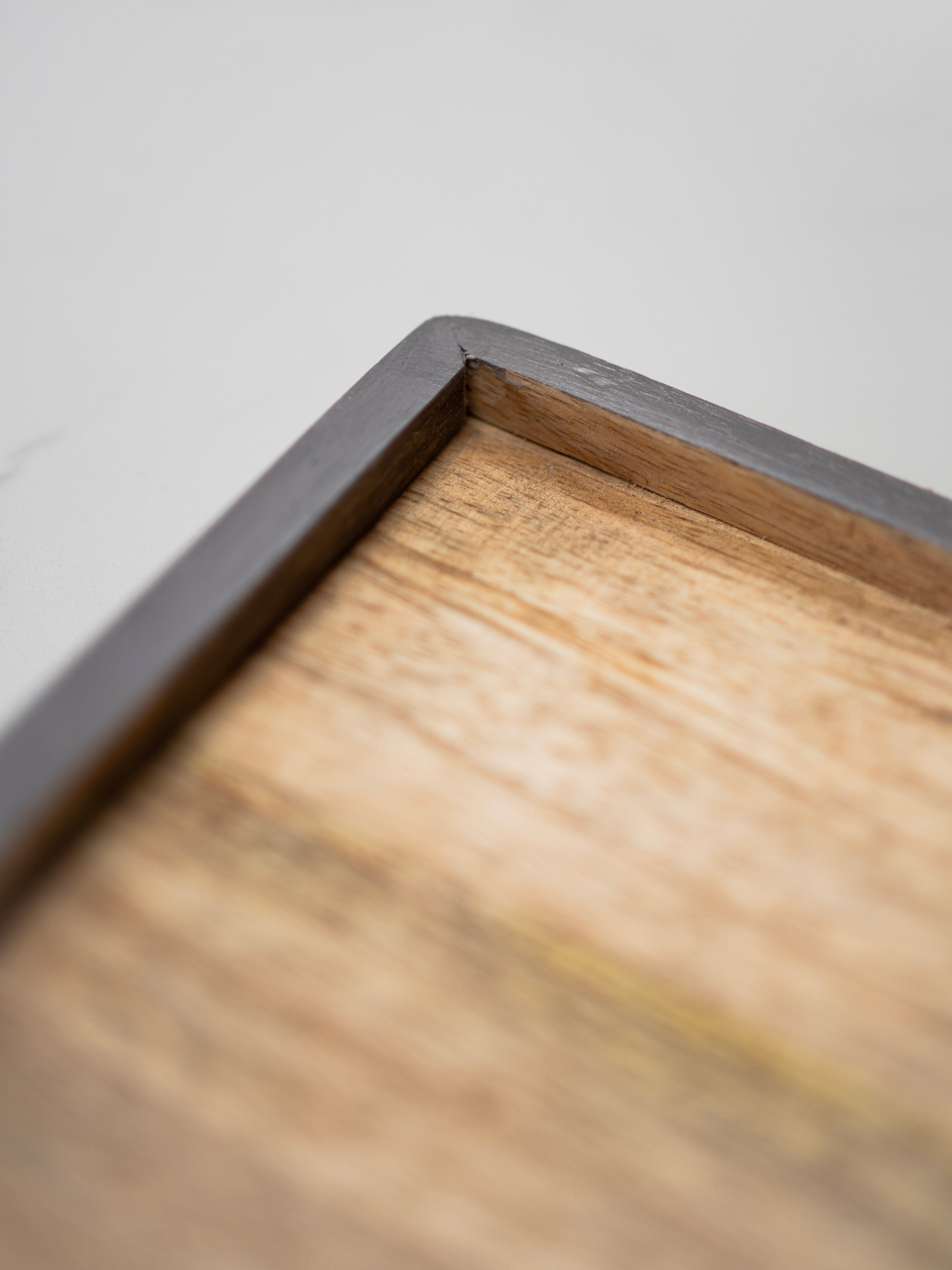 Close-up of a wooden tray with a grey frame corner.