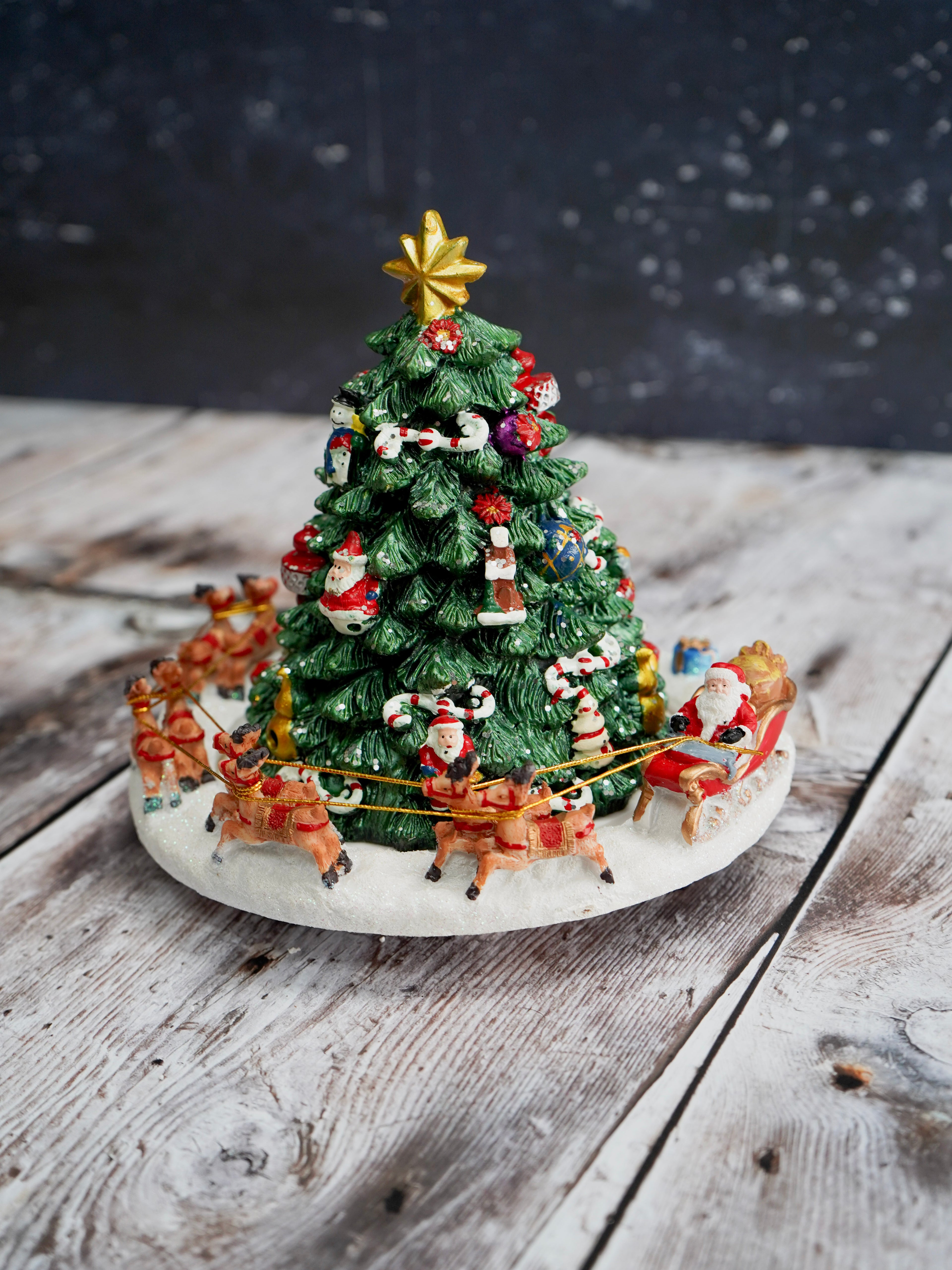 Decorative Christmas tree with animated figures on a wooden surface