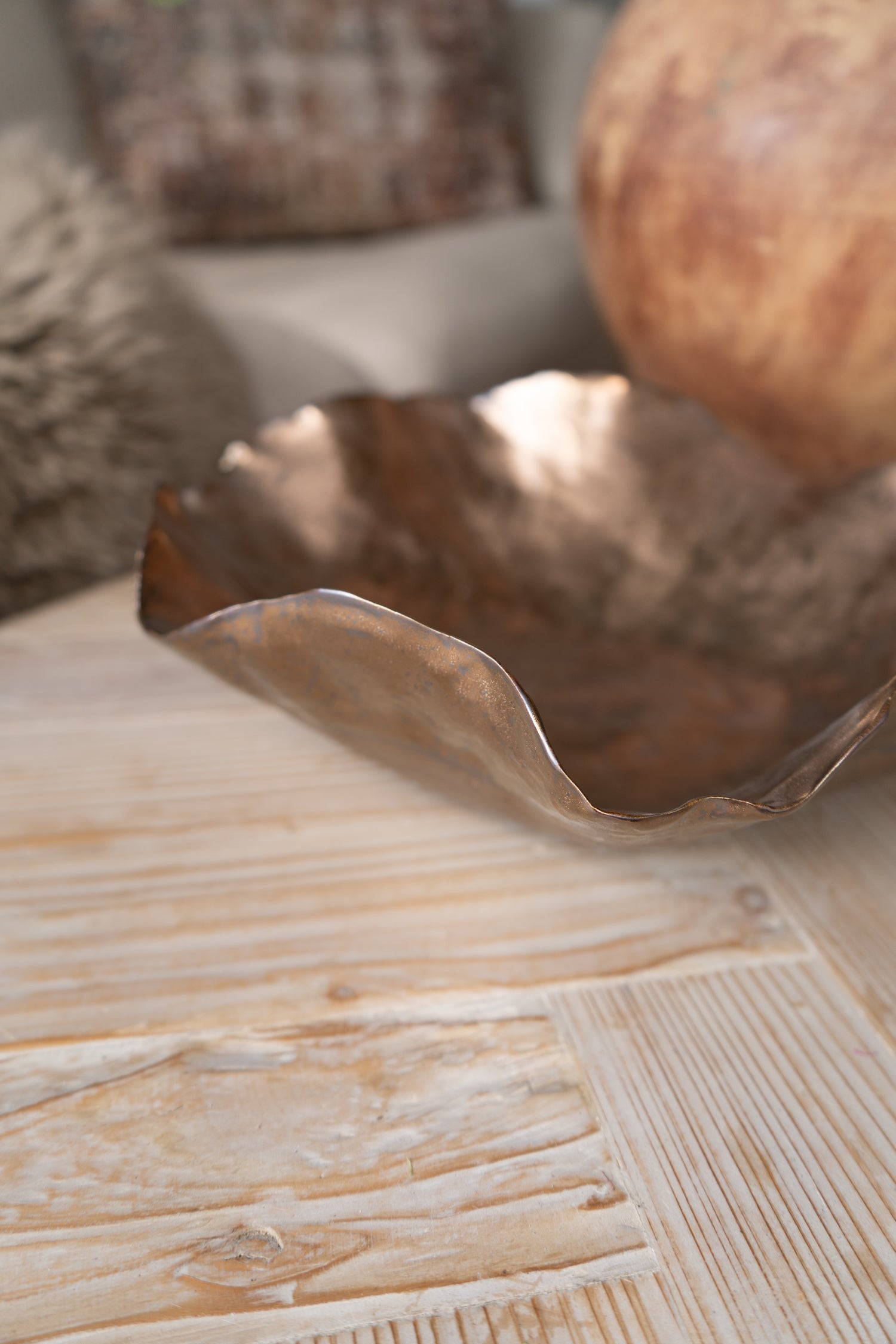 Decorative metallic bowl on a wooden surface with a blurred background