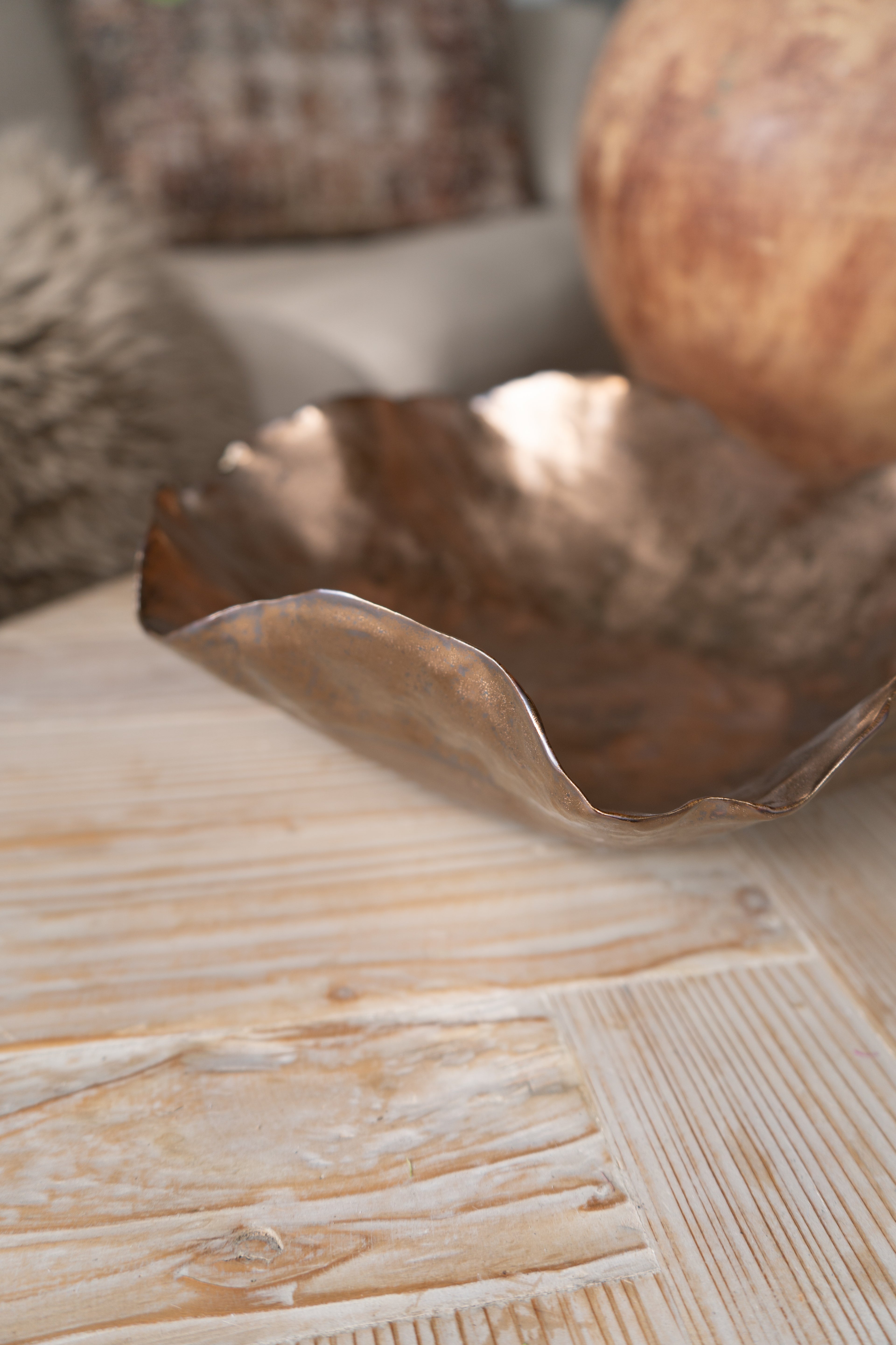 Decorative metallic bowl on a wooden surface with a blurred background