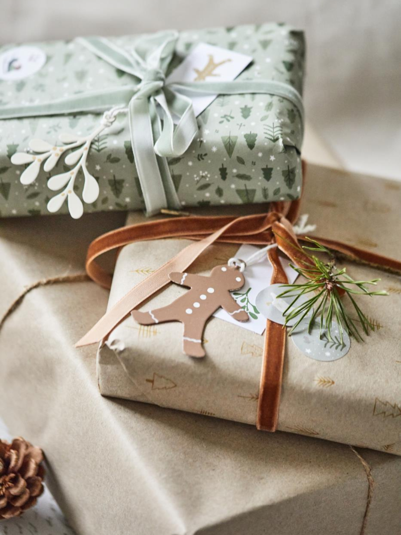 Two wrapped gifts on a textured surface with decorative ribbons and tags.