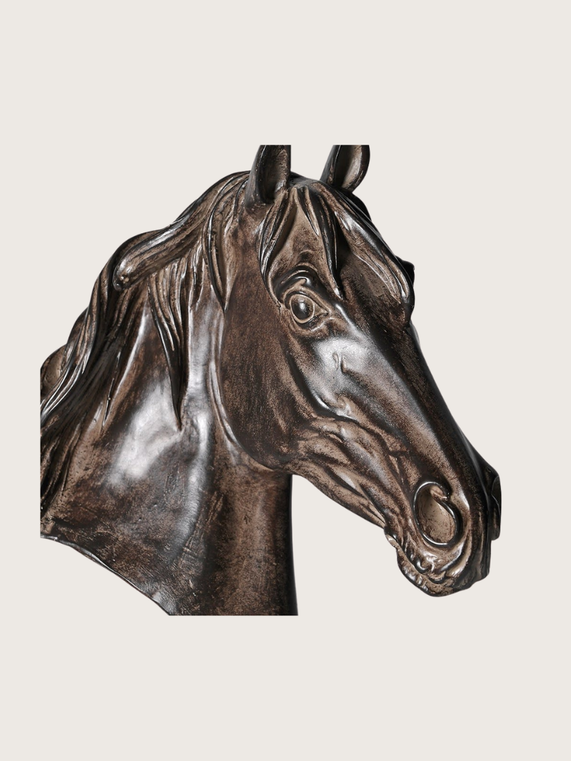 Bronze sculpture of a horse head on a beige background