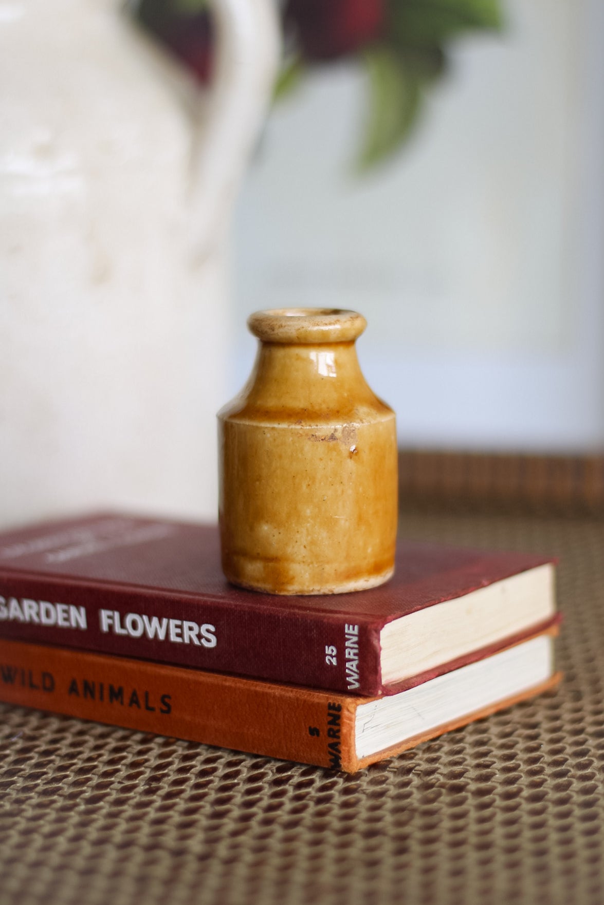 Small brown ceramic bottle on top of two books with a blurred background