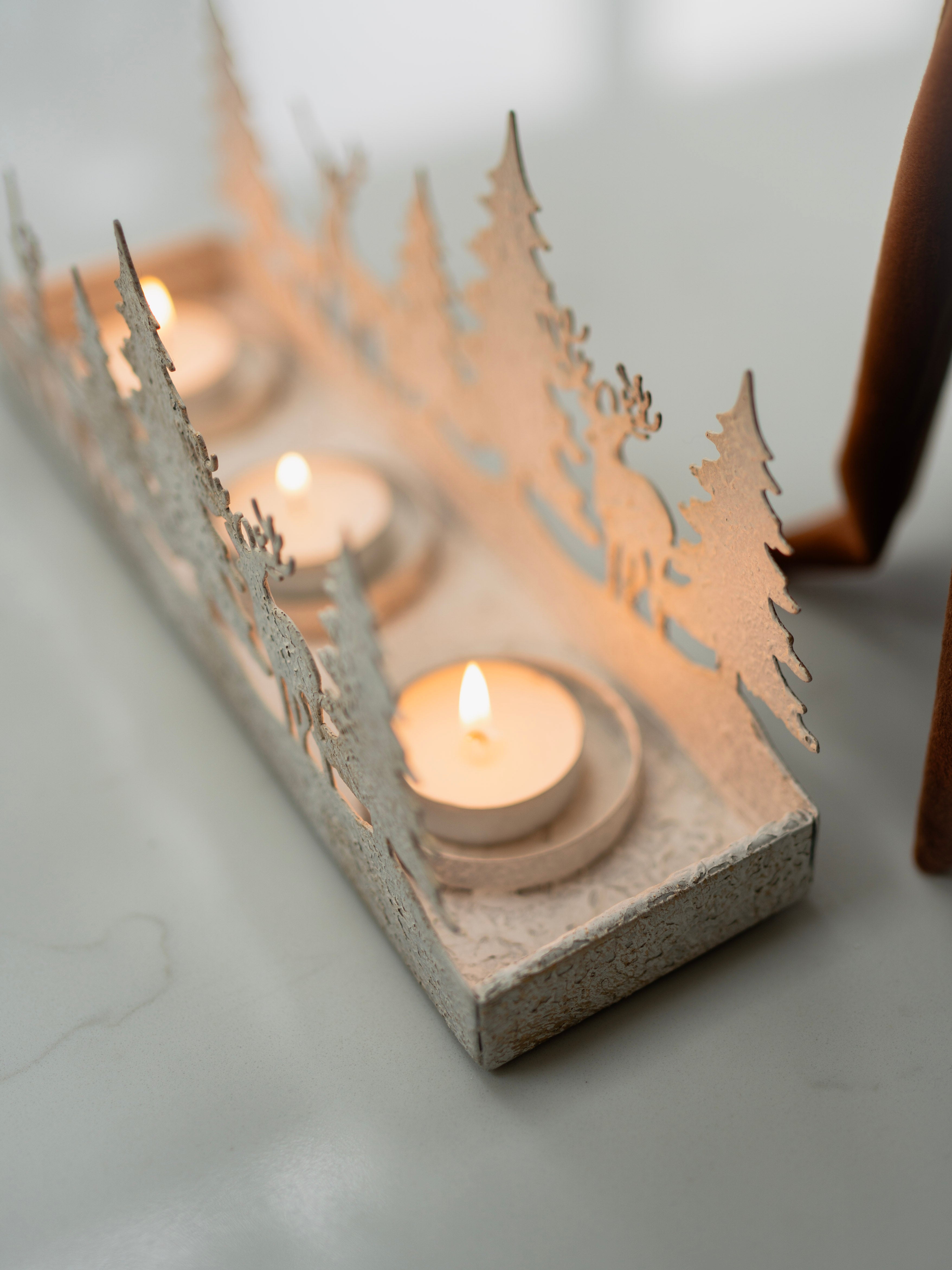 Decorative candle holder with cut-out designs on a white surface