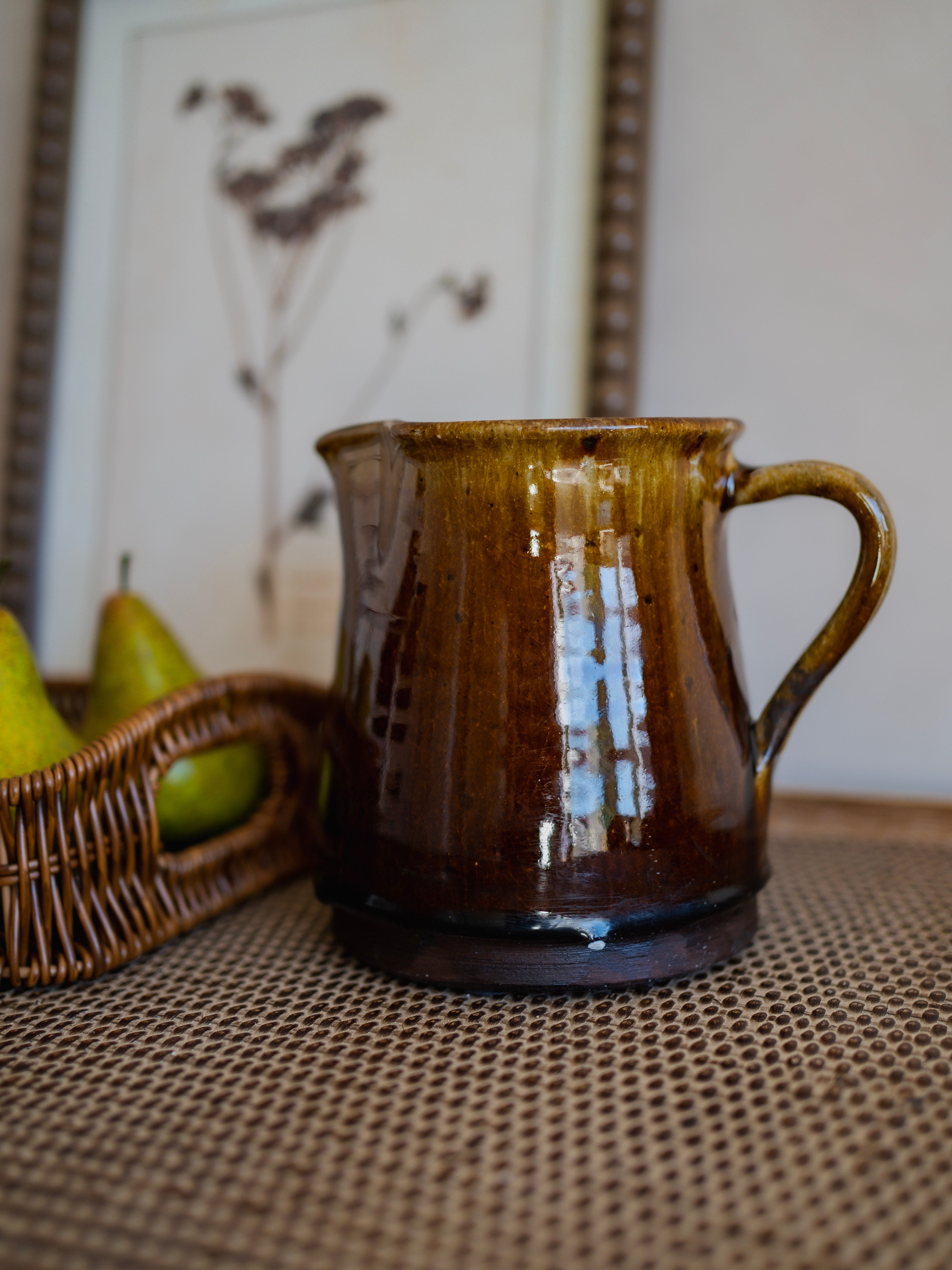 Brown ceramic jug on a textured surface with a blurred background
