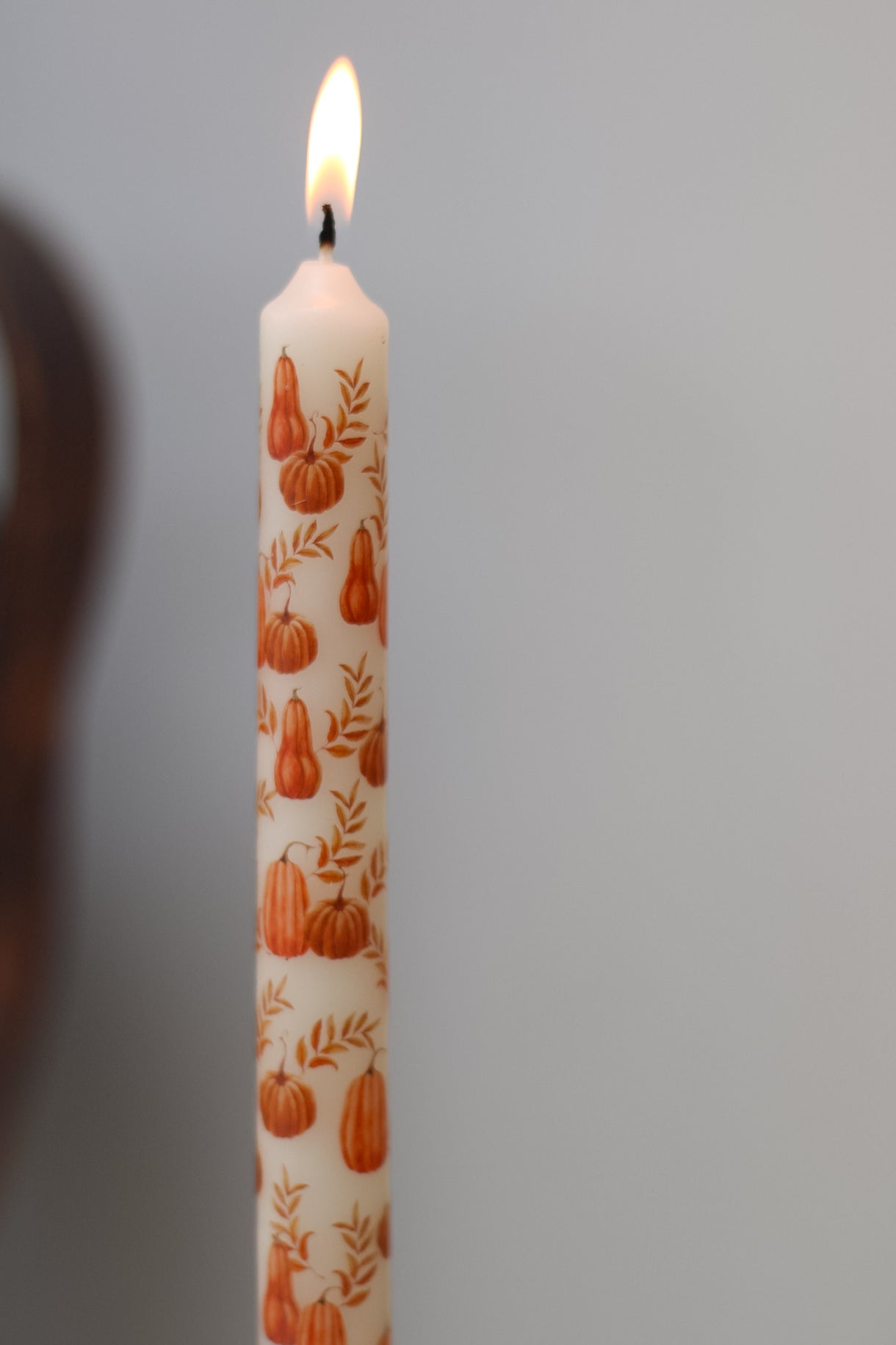 Candle with pumpkin pattern on a grey background