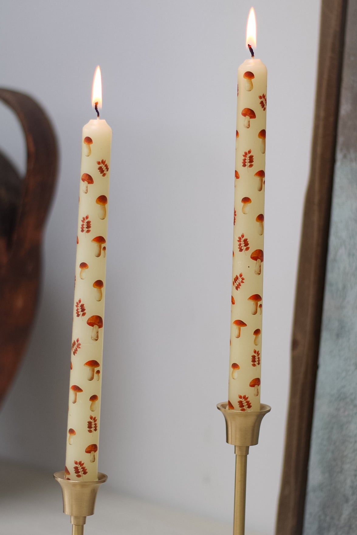 Two candles with mushroom pattern on a plain background
