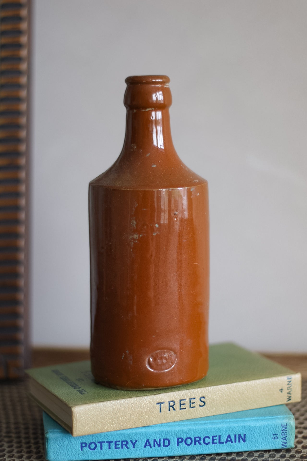 Brown ceramic bottle on top of books with a blurred background
