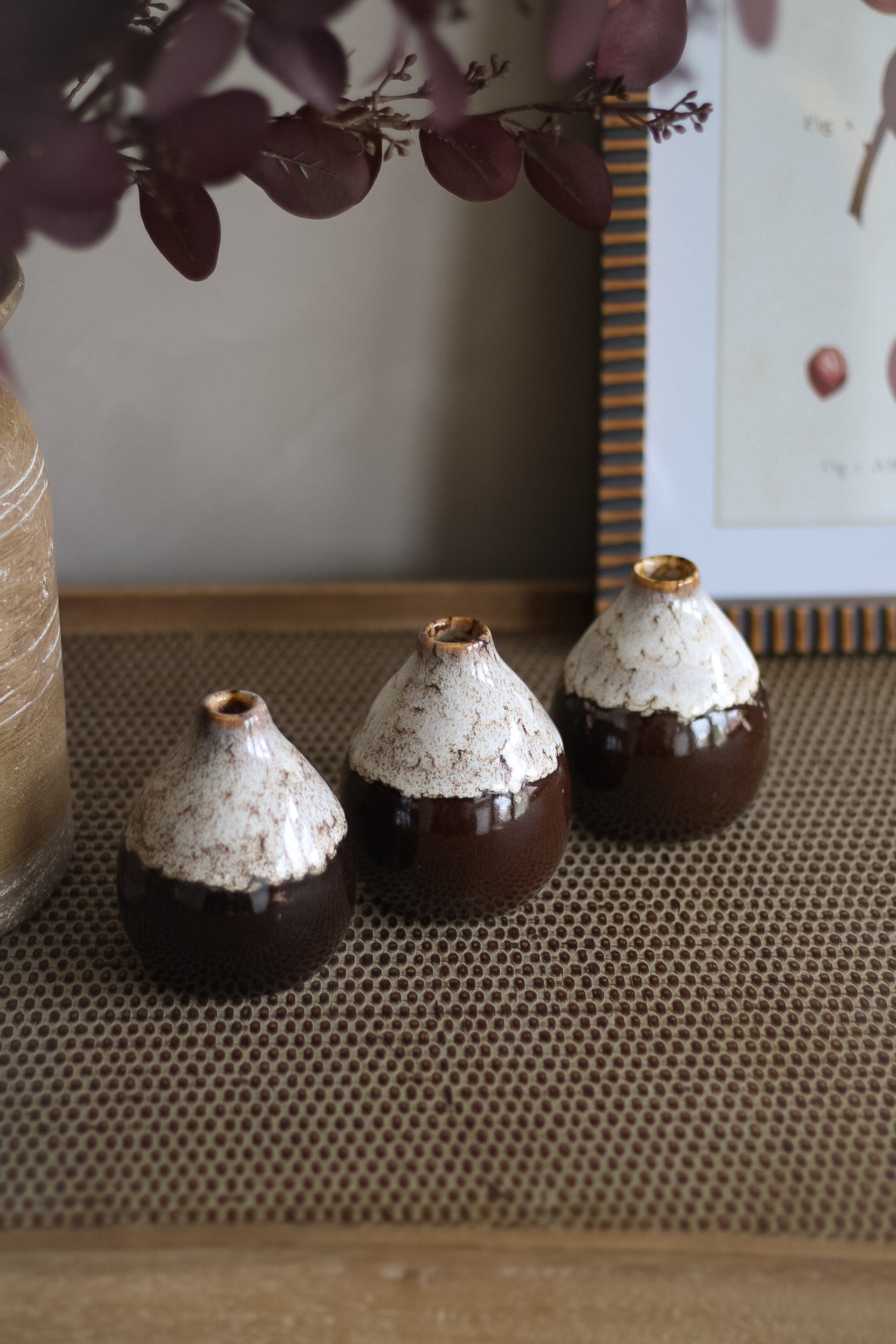 Three speckled brown small ceramic pots with textured tops on a textured surface.