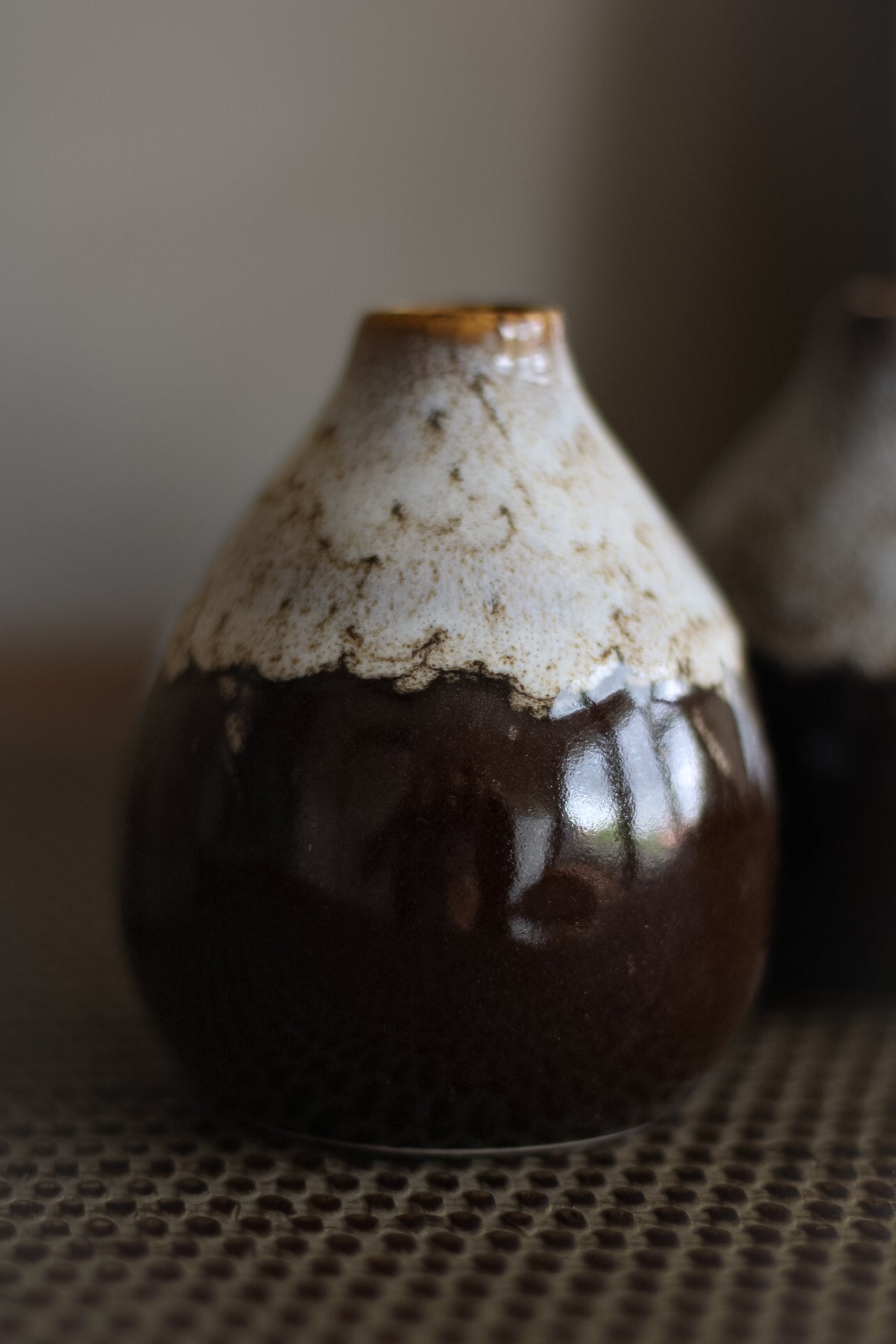 Bud vase with a unique design on a textured surface