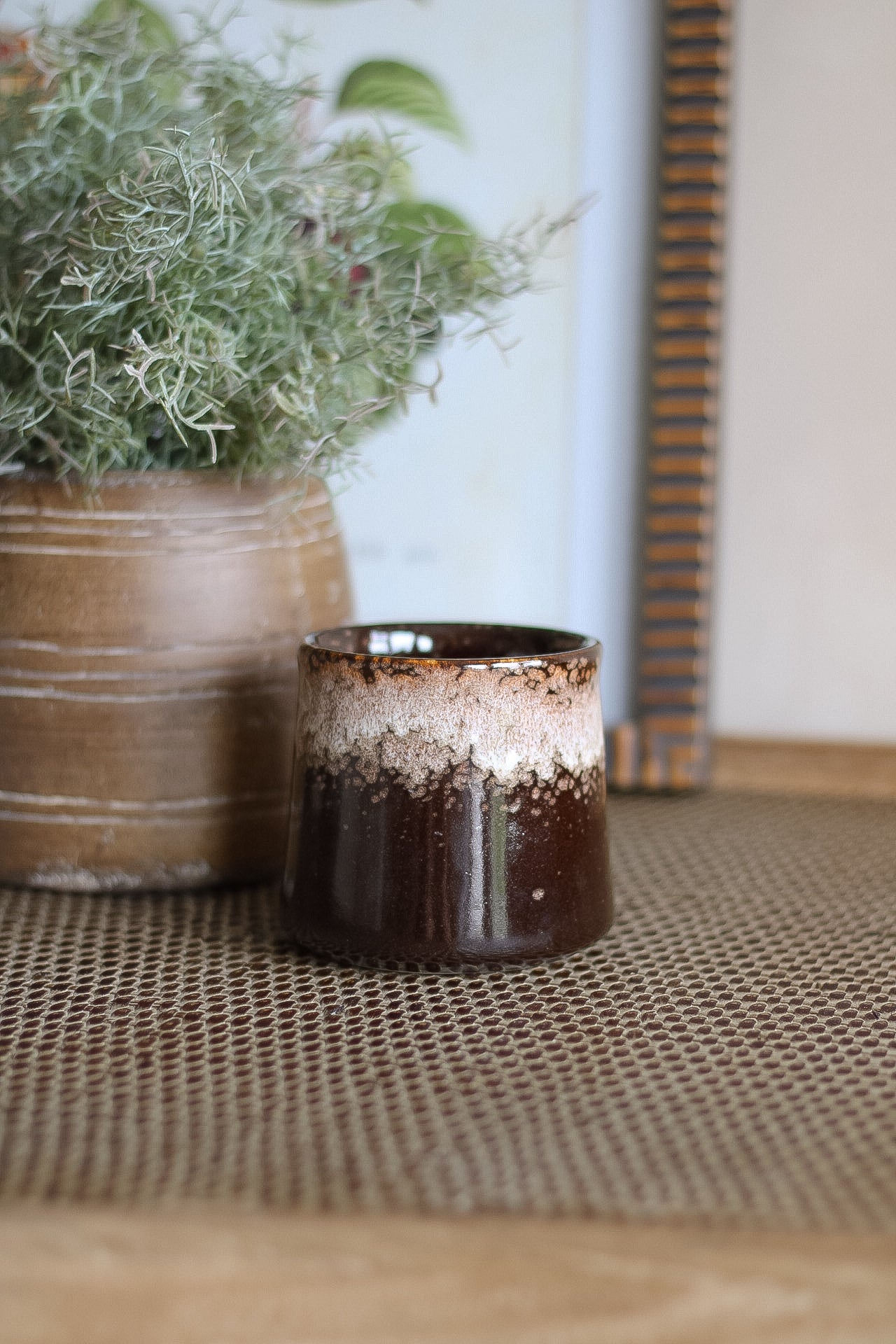 Brown ceramic pot with a textured surface on a woven mat