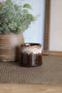 Brown ceramic pot with a textured surface on a woven mat