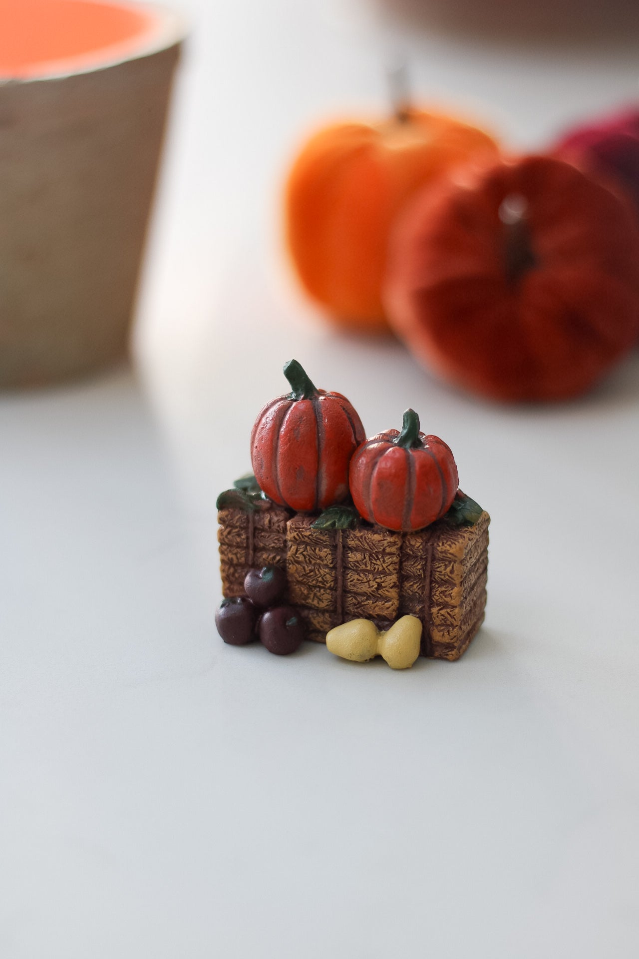 Miniature pumpkins and gourds on a hay bale structure with blurred pumpkins in the background.