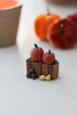 Miniature pumpkins and gourds on a hay bale structure with blurred pumpkins in the background.