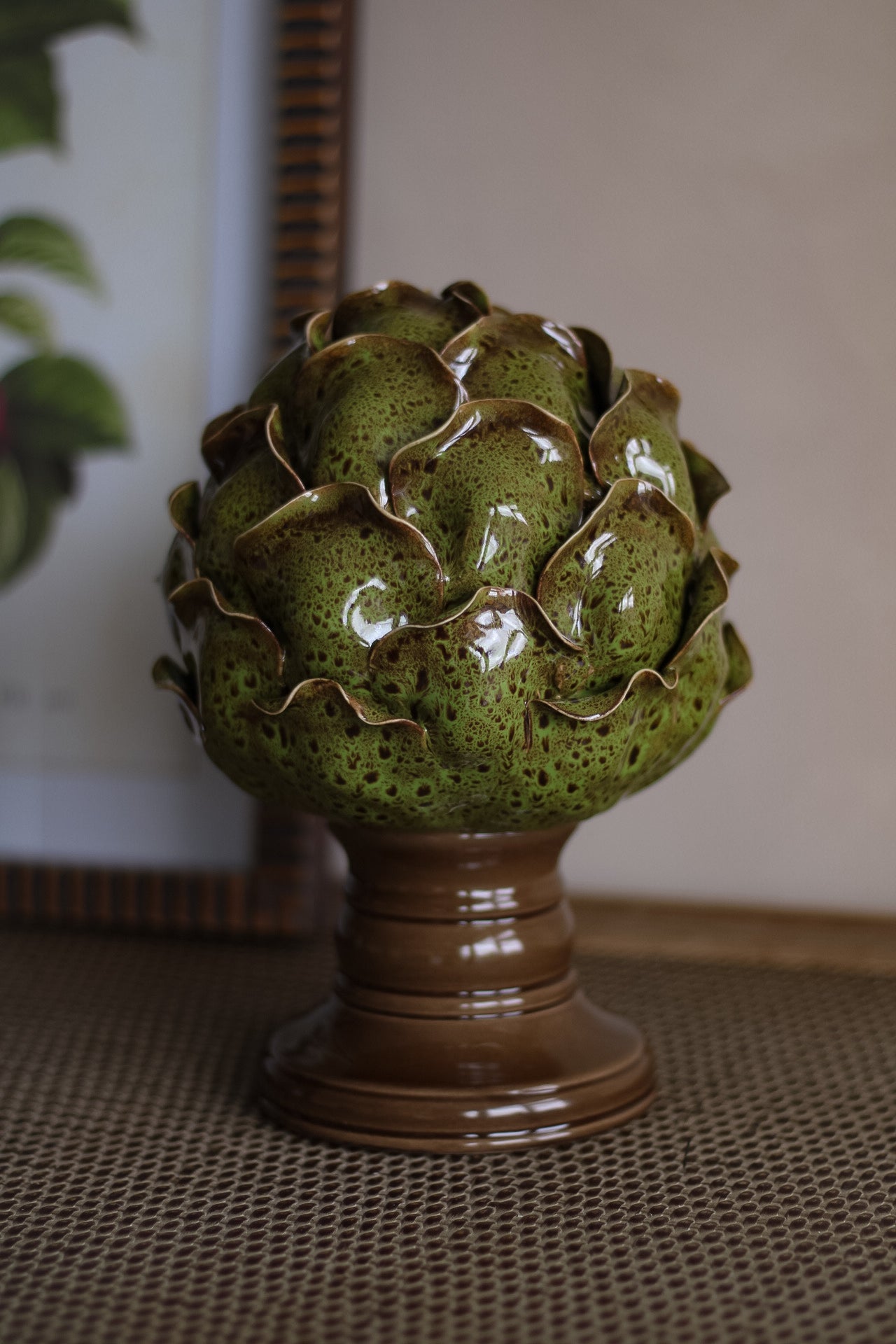 Decorative ceramic artichoke on a pedestal with a neutral background