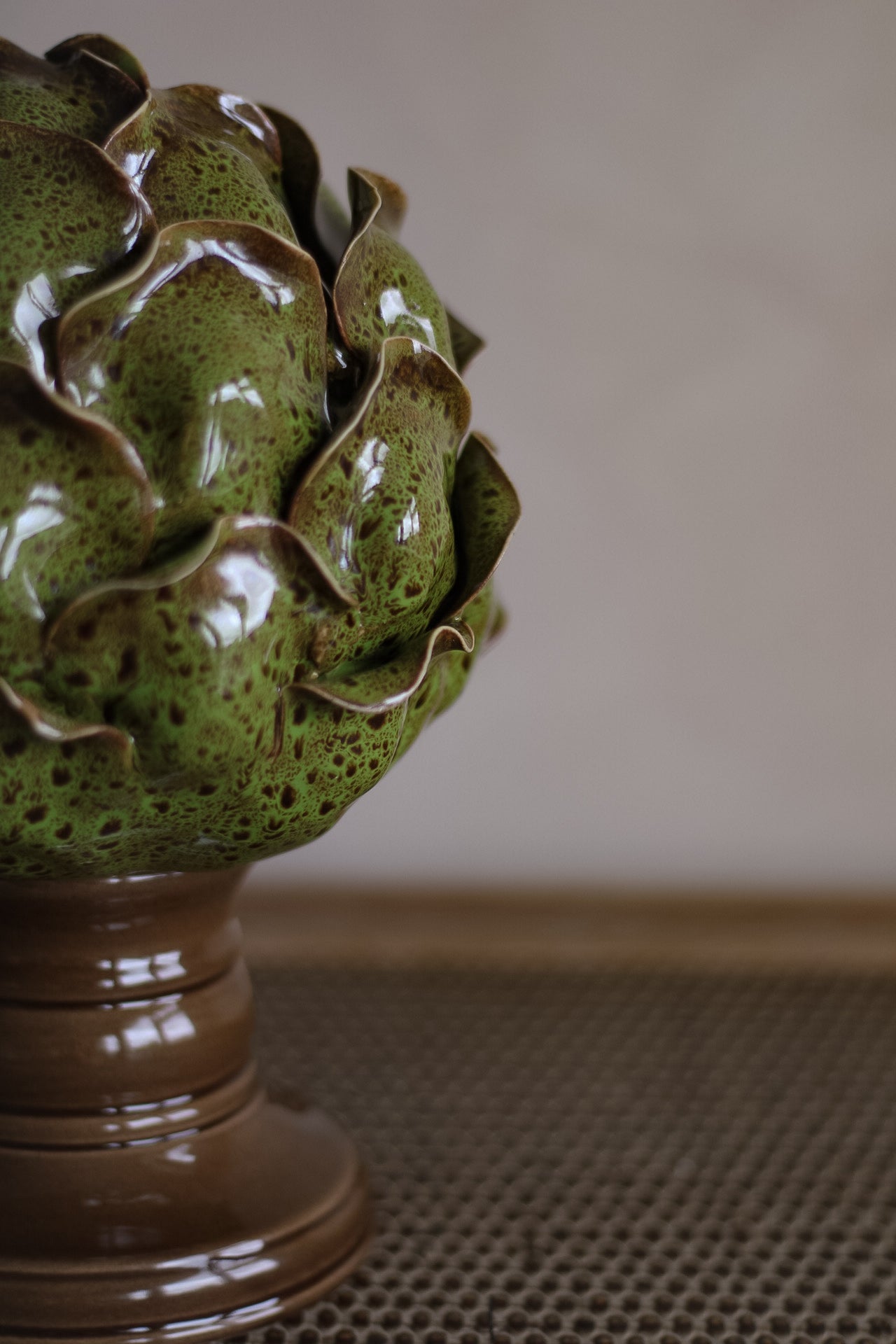 Ceramic artichoke sculpture on a pedestal with a neutral background