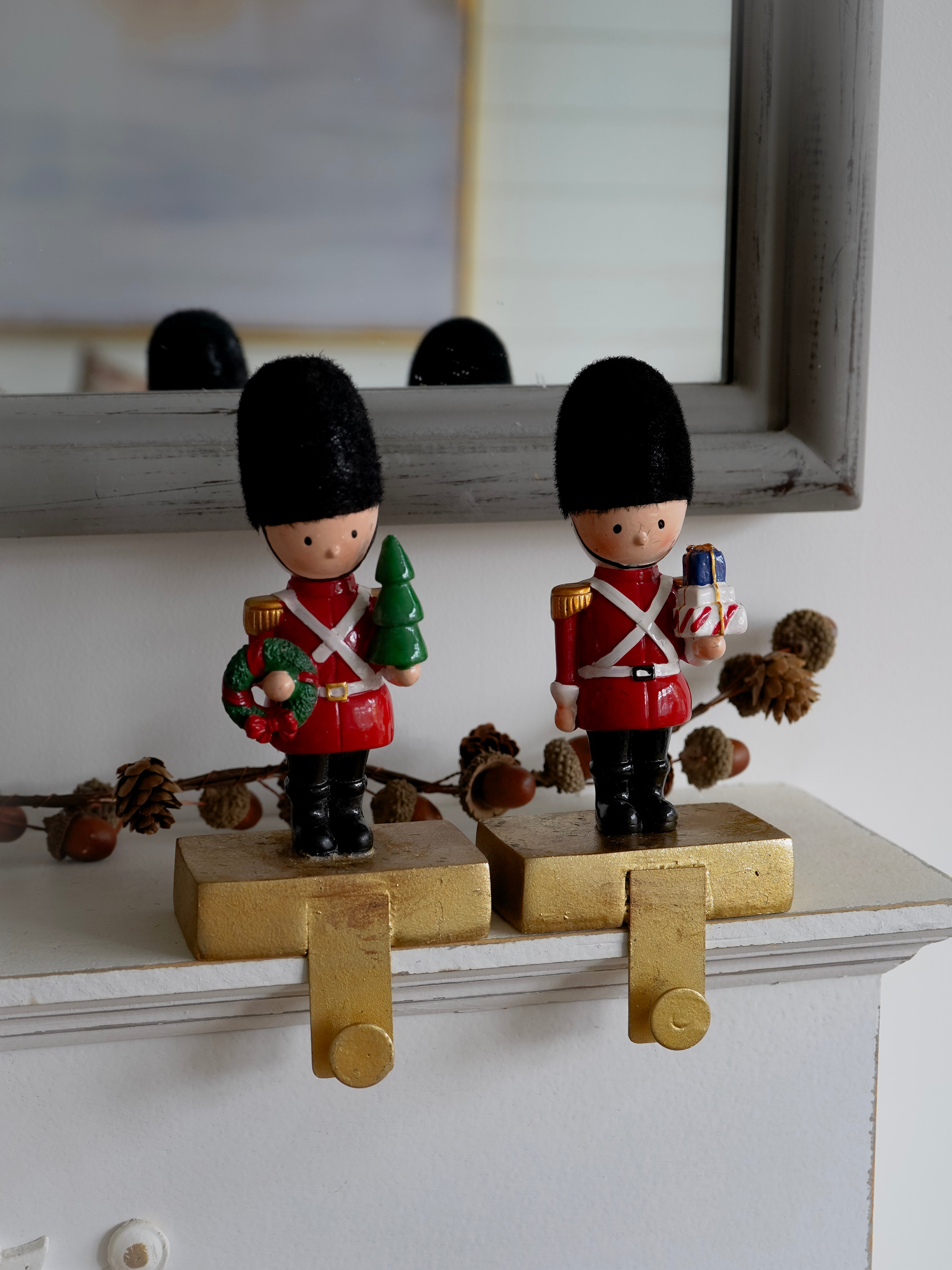 Two toy soldiers in red uniforms with black hats on a decorative stand.