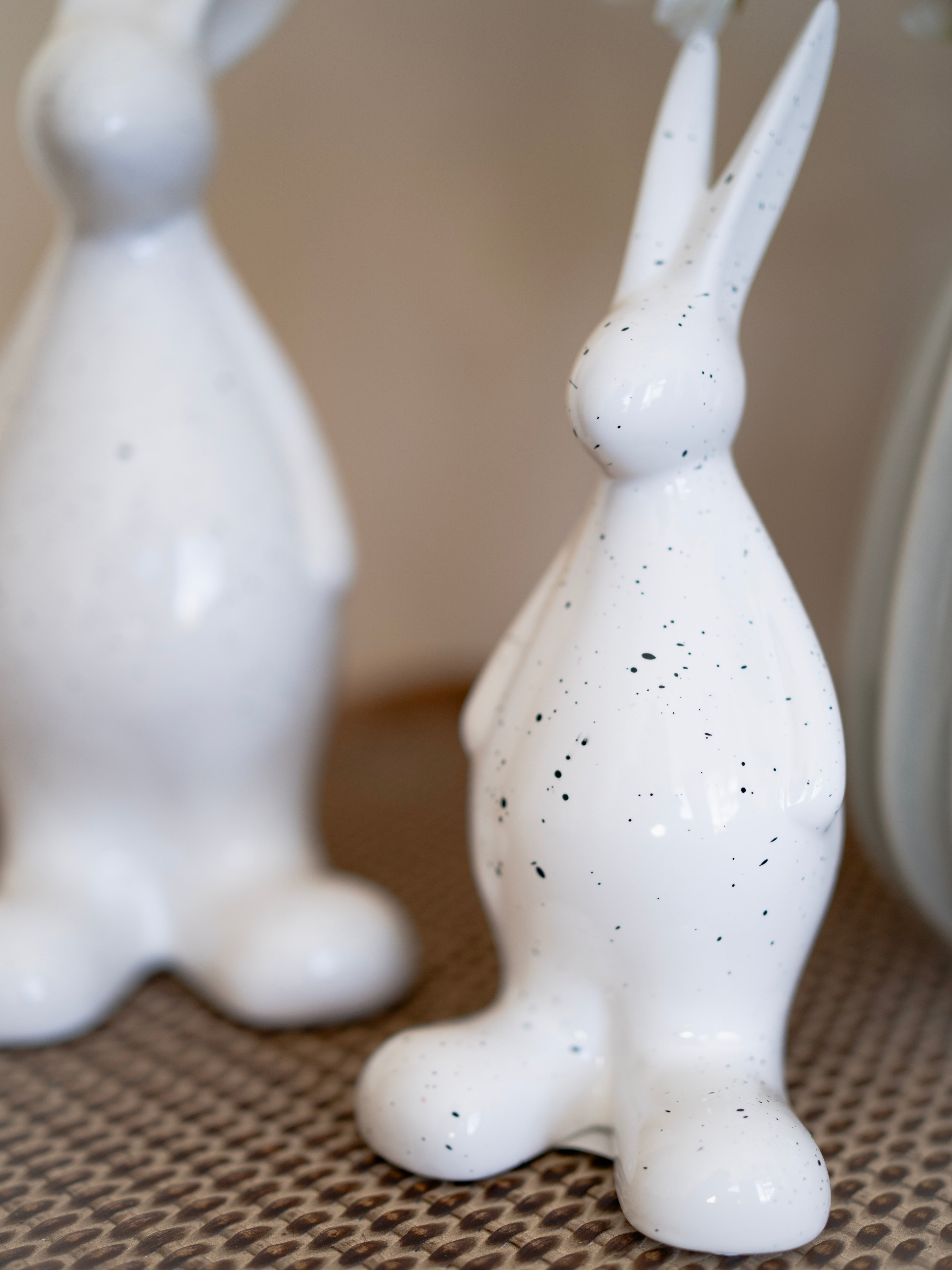 White ceramic rabbit figurines with speckled texture on a textured surface.